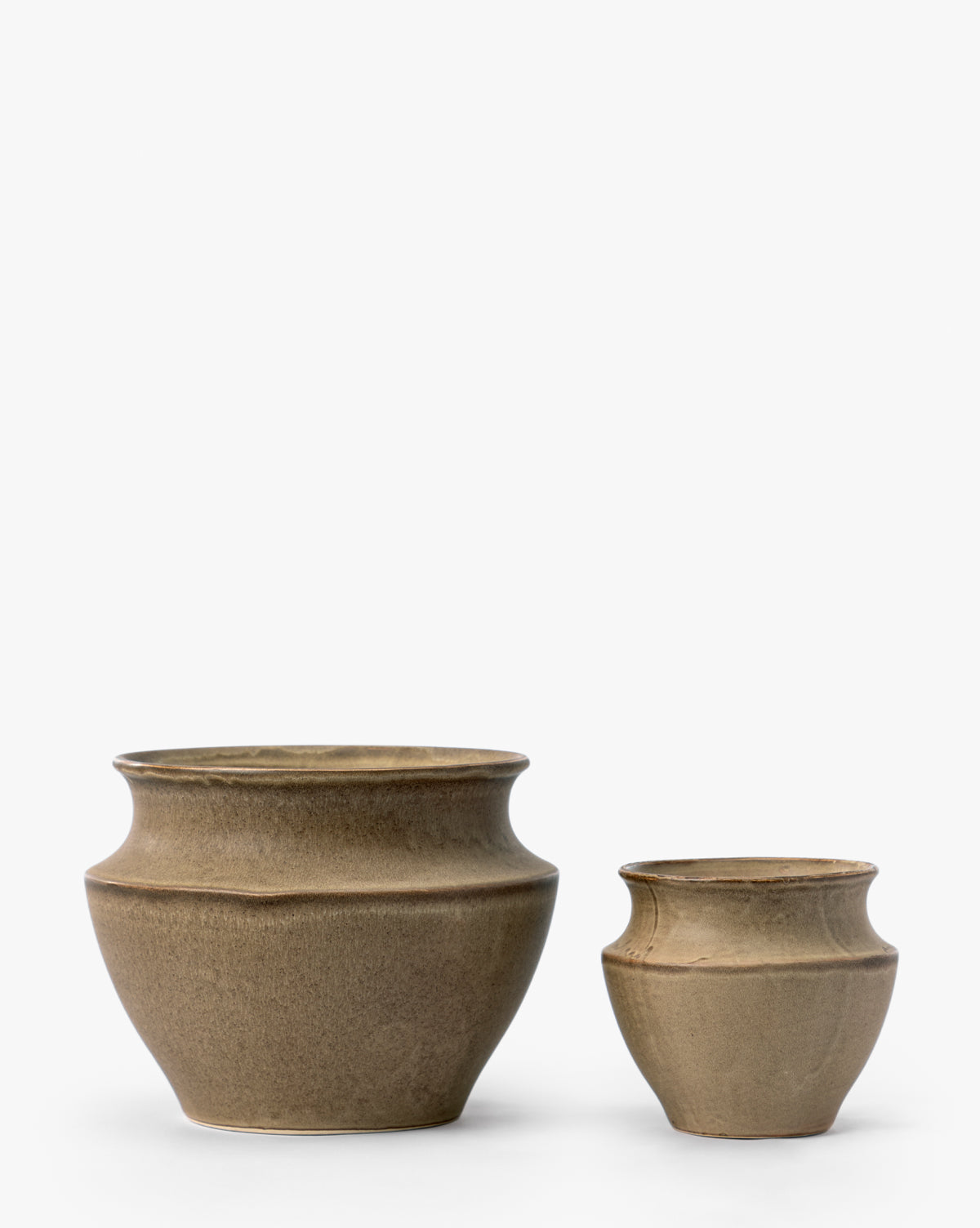 Two brown ceramic pots, including the larger Liora Pot with a wide, round body and slightly flared rim, are placed side by side on a white background; the Liora Pot serves as an elegant decorative planter next to the smaller pot, by McGee & Co.