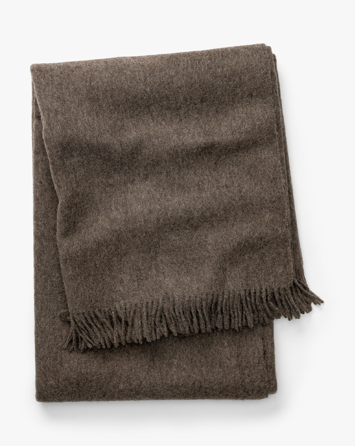 Certainly! Here’s the revised sentence with McGee & Co. blended at the end: The Fibre Locester Throw, a brown recycled alpaca blanket with fringed edges, is shown folded against a white background, McGee & Co.