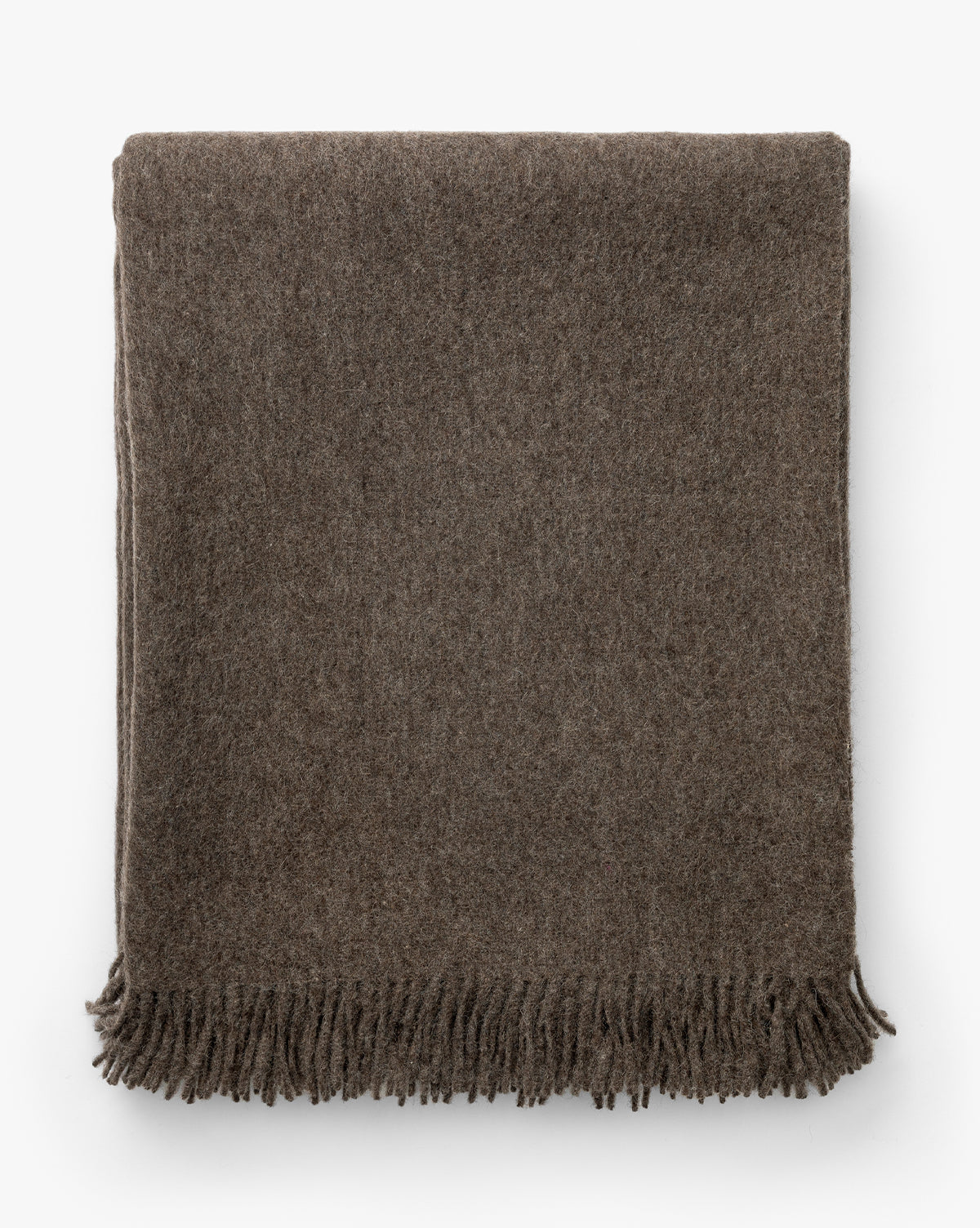 The Fibre Locester Throw is a neatly folded, brown recycled alpaca blanket with short fringe along the bottom edge, displayed on a white background. McGee & Co.