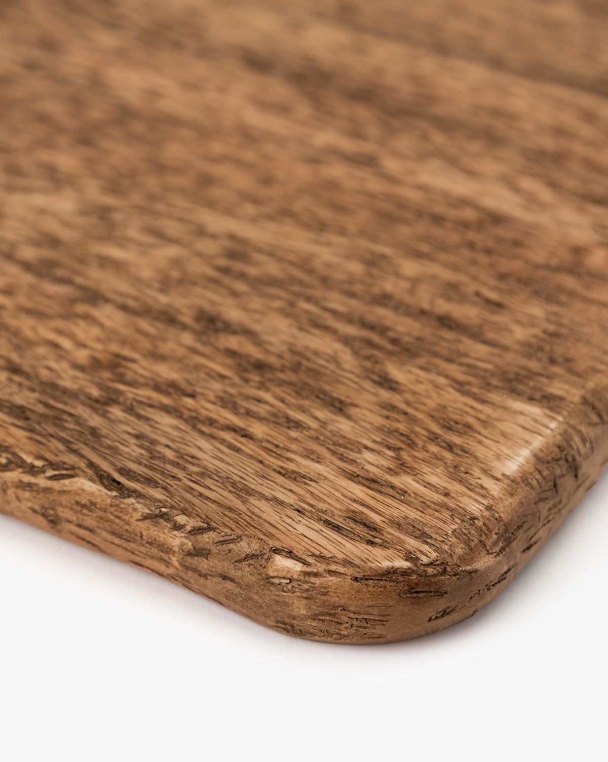 Close-up of the Longfellow Breadboard’s corner, showcasing its rich brown mango wood grain, smooth finish, and rounded edge—ideal as kitchen decor or a stylish serving board on a white background, by McGee & Co.