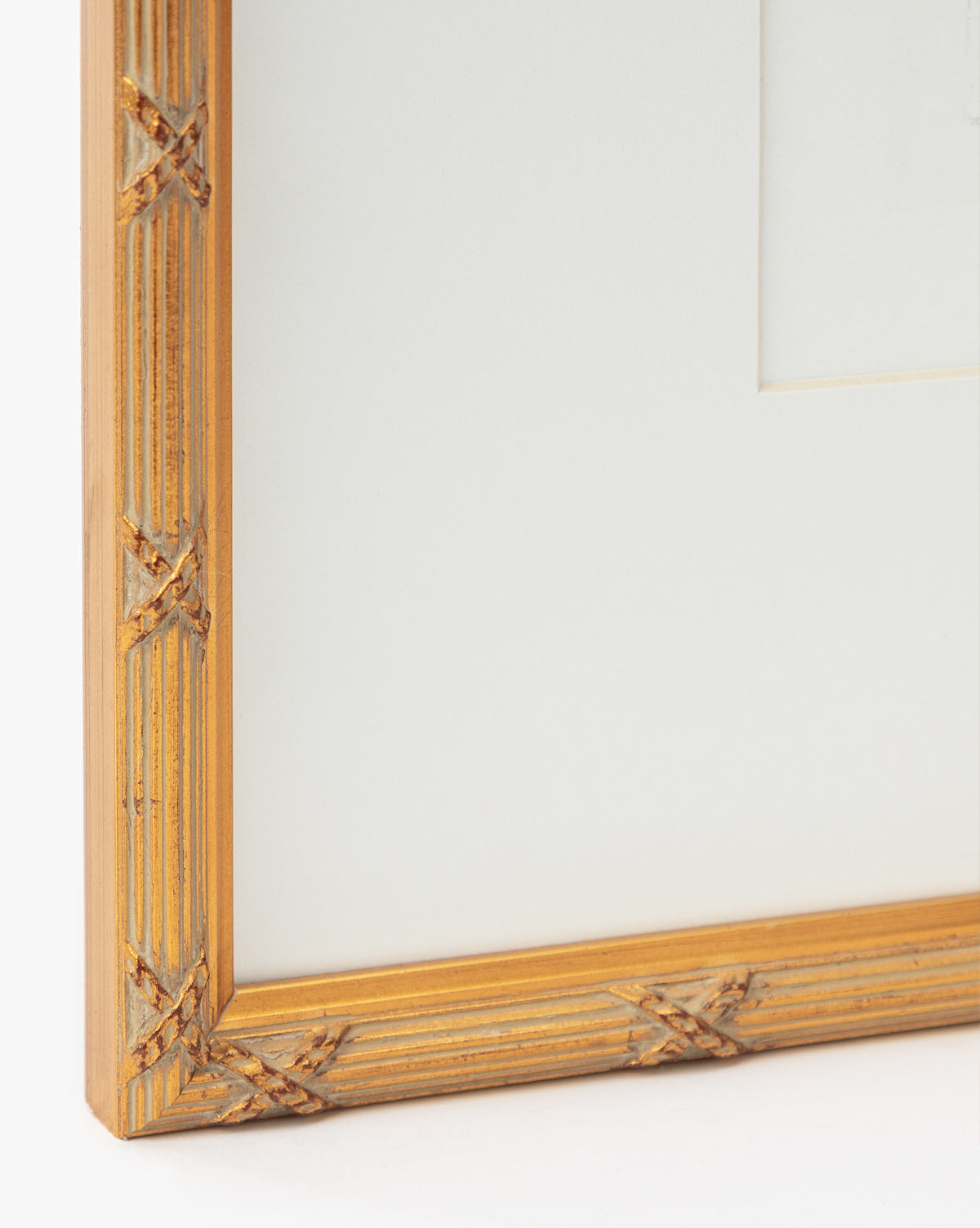 Close-up of the Loose Ribbons golden frame featuring a ribbed texture and crisscross corners, ideal for displaying giclee prints or artwork in a childs room, shown with a white mat board, by McGee & Co.