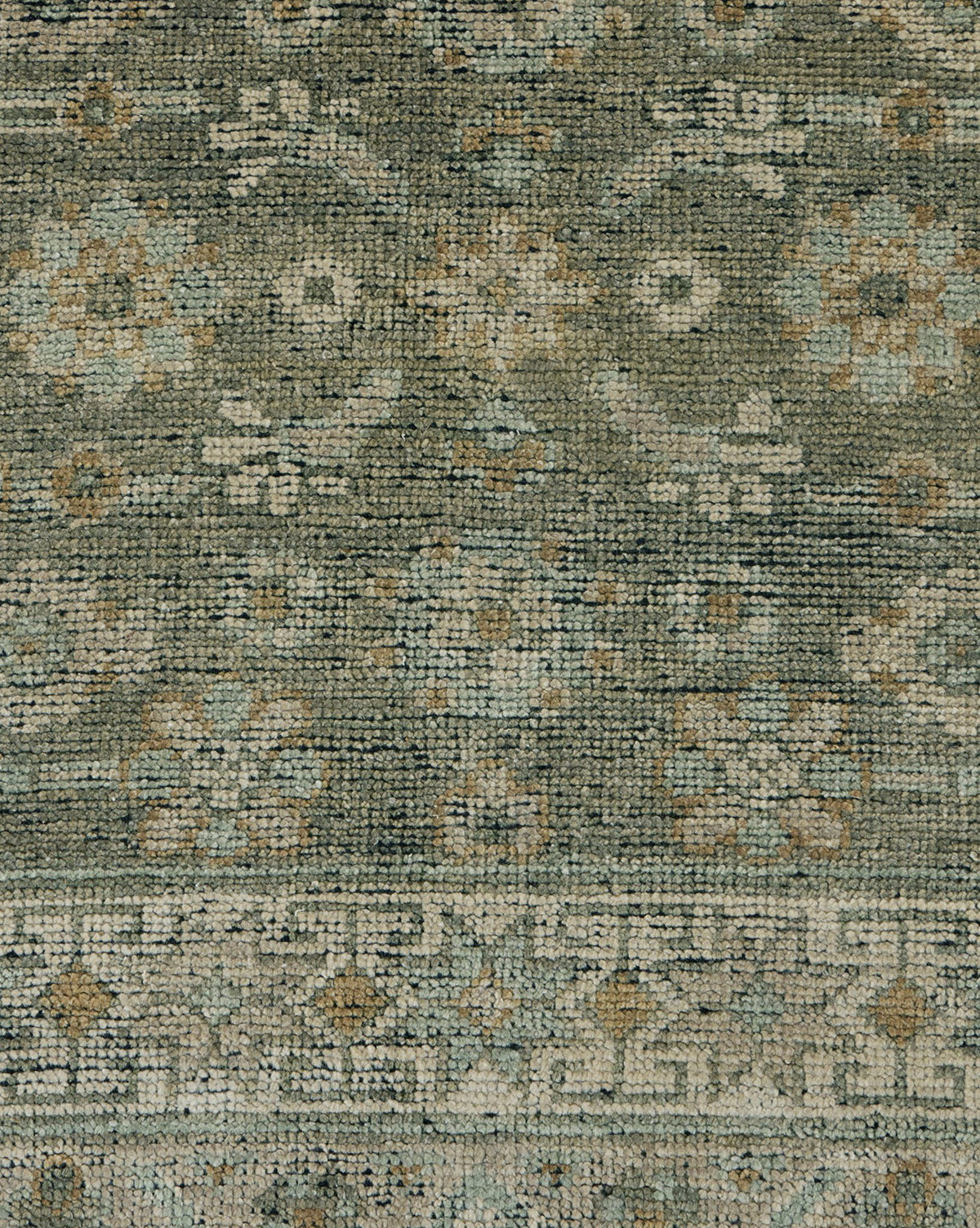 A close-up of the Loreo Hand-Knotted Wool Rug highlights its intricate geometric and floral patterns in soft green, beige, and blue tones, showcasing the artisan craftsmanship and detailed woven texture, by McGee & Co.