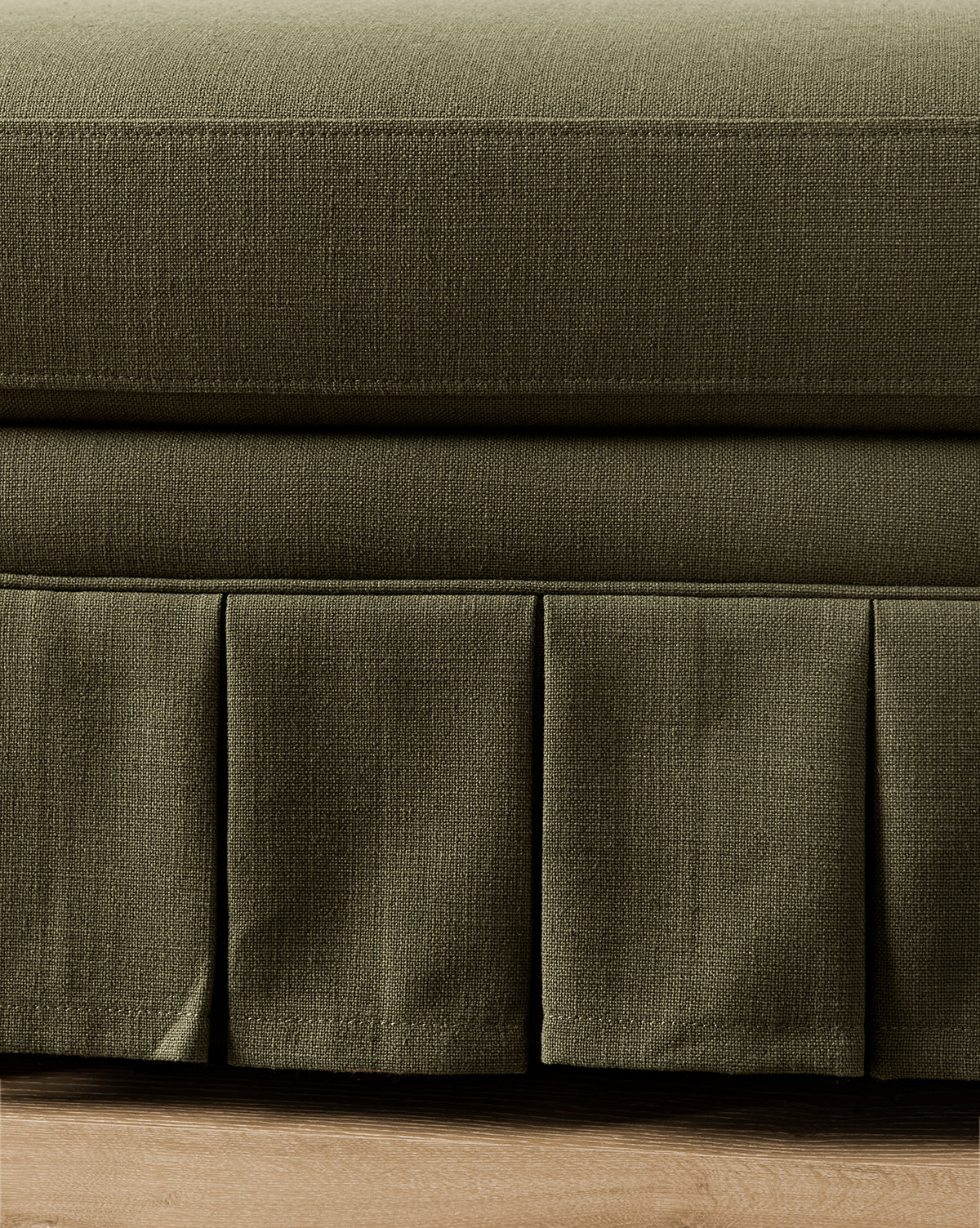 Close-up of a green fabric bed skirt on a bed with wooden flooring from McGee & Co.