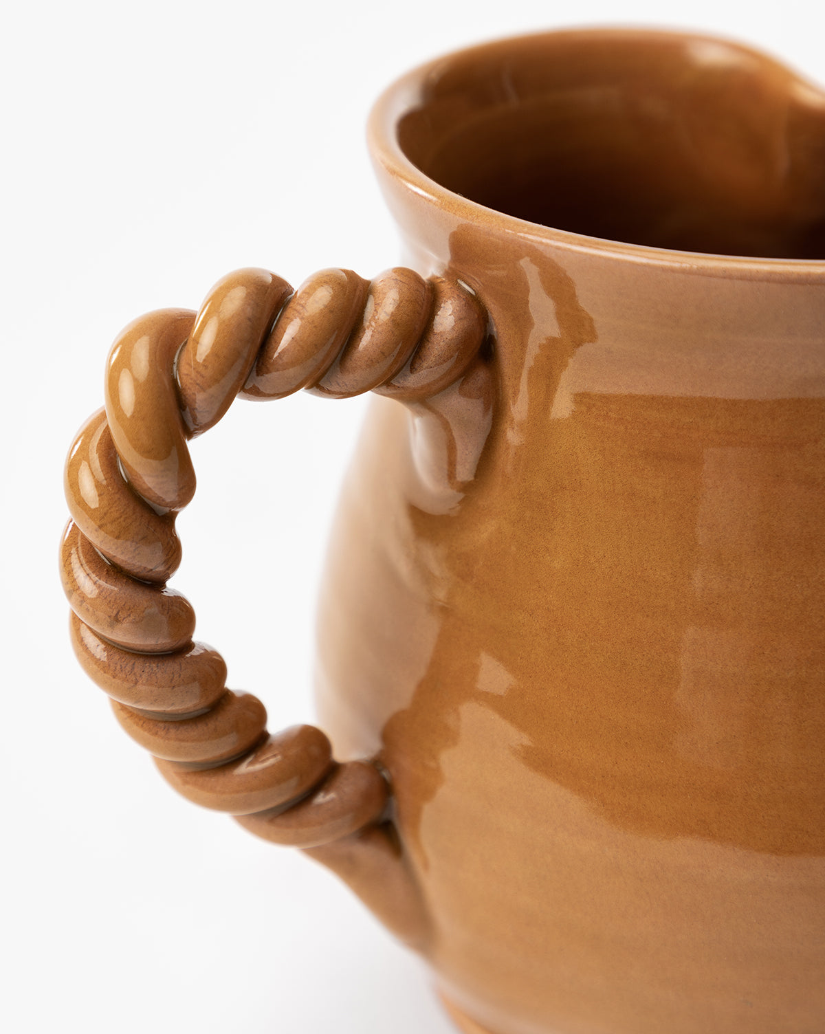 Close-up of the Louise Jug, featuring brown terracotta with an earthenware glaze and a twisted, rope-like handle, set against a white background by McGee & Co.