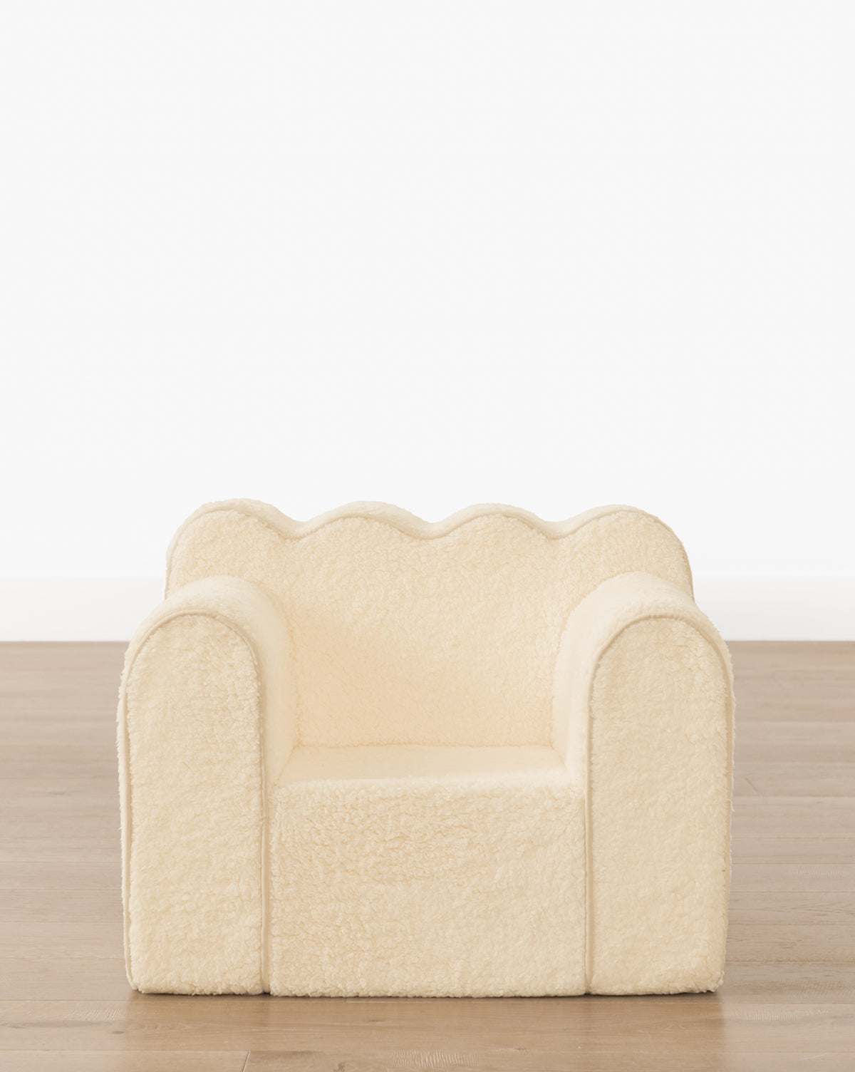 The Luciana Kids Chair, a small cream-colored sherpa seat with a scalloped backrest and rounded armrests, features a soft foam interior—perfect for cozy comfort in any child’s space, by McGee & Co.
