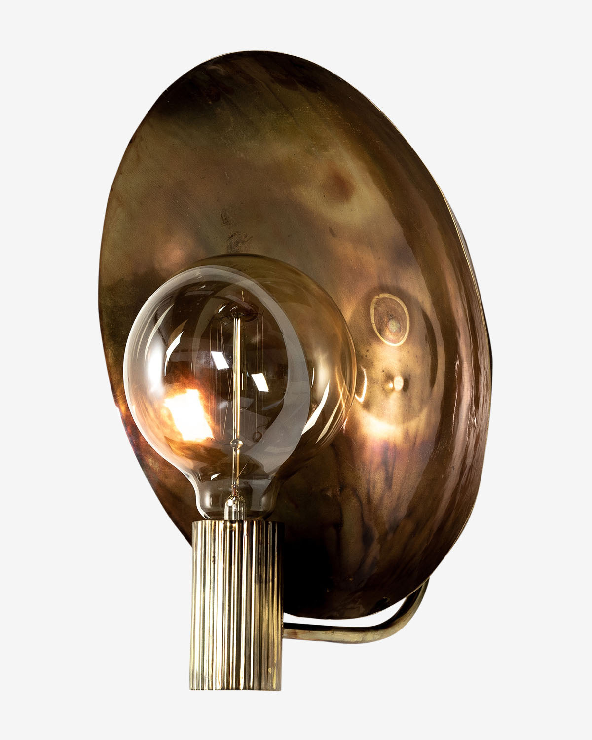 The Lund Sconce by Four Hands features a round brass backplate and a vertical, ribbed brass socket with a clear bulb. Its warm, reflective patina makes it an ideal choice for adding contemporary lighting to any space. McGee & Co.
