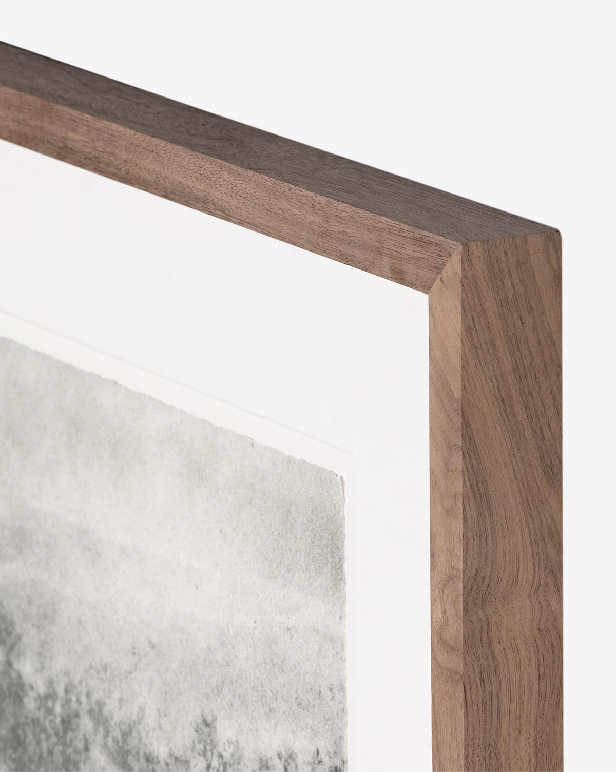 Close-up of the top corner of a wooden frame with a natural wood grain finish, displaying Hill Country Study I by Aileen Fitzgerald with a white mat and textured grayscale art reminiscent of a charcoal drawing.