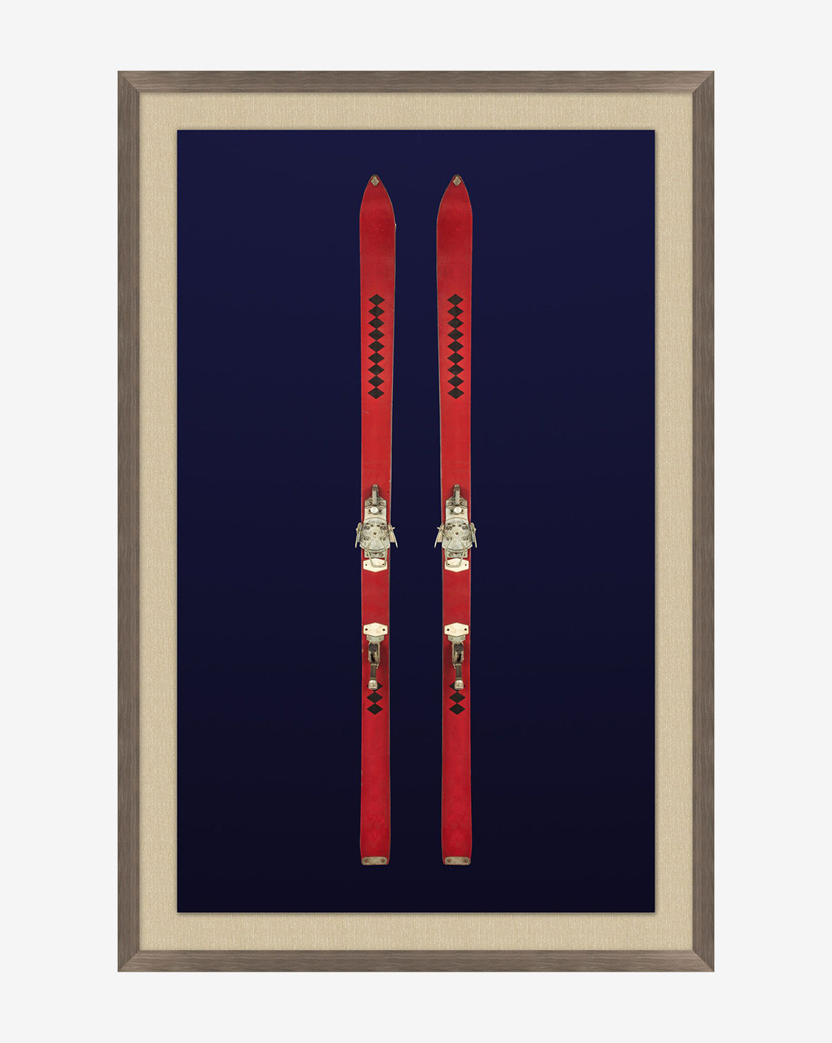 Antique Navy Skis II showcases two vintage red skis with metal bindings, displayed upright against a dark blue background in a chic walnut woodgrain frame.