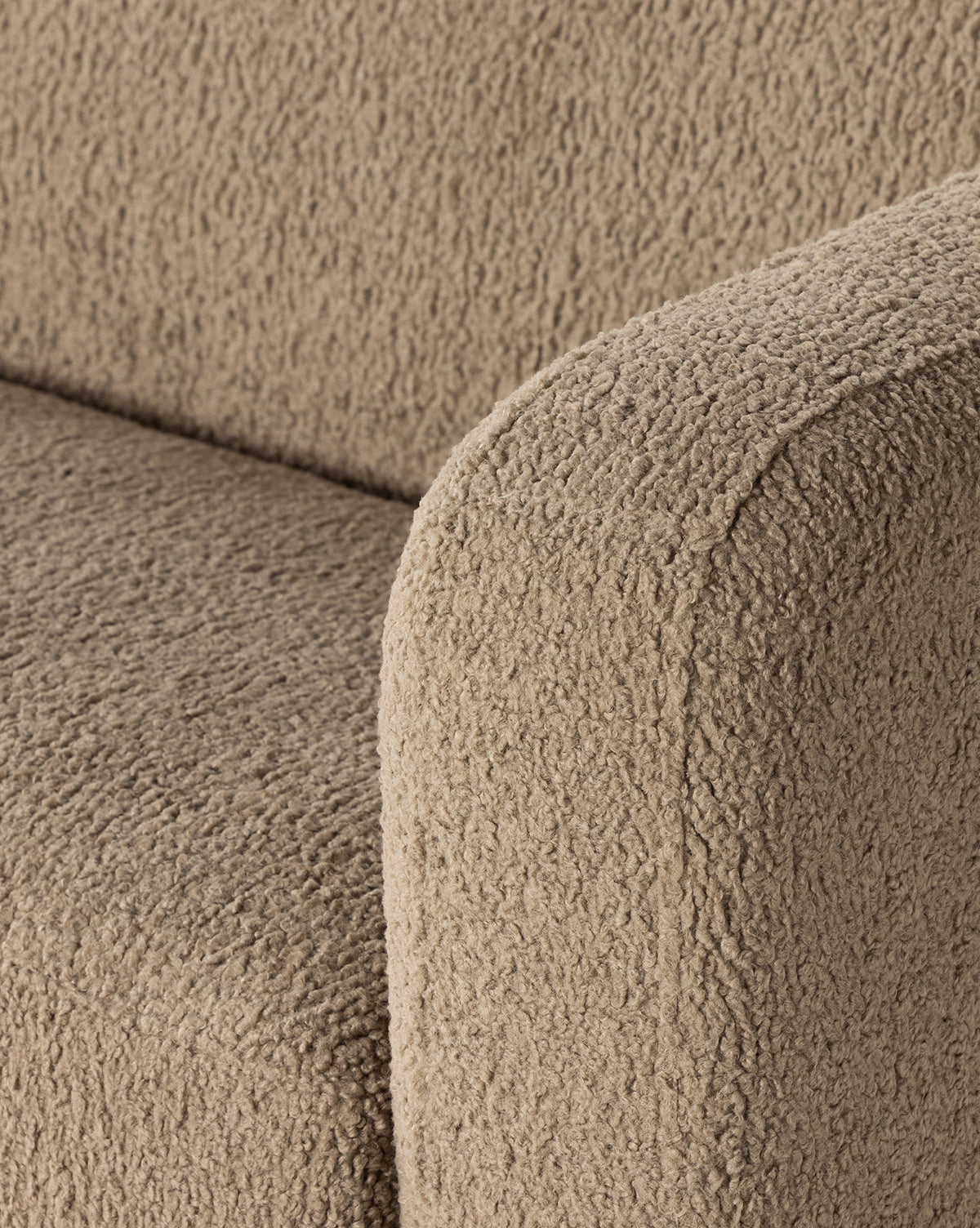 Close-up of the arm and seat of the Quill Sofa 84 by Four Hands, featuring beige faux shearling upholstery thats soft, plush, and slightly curly, evoking vintage sofa designs. McGee & Co.