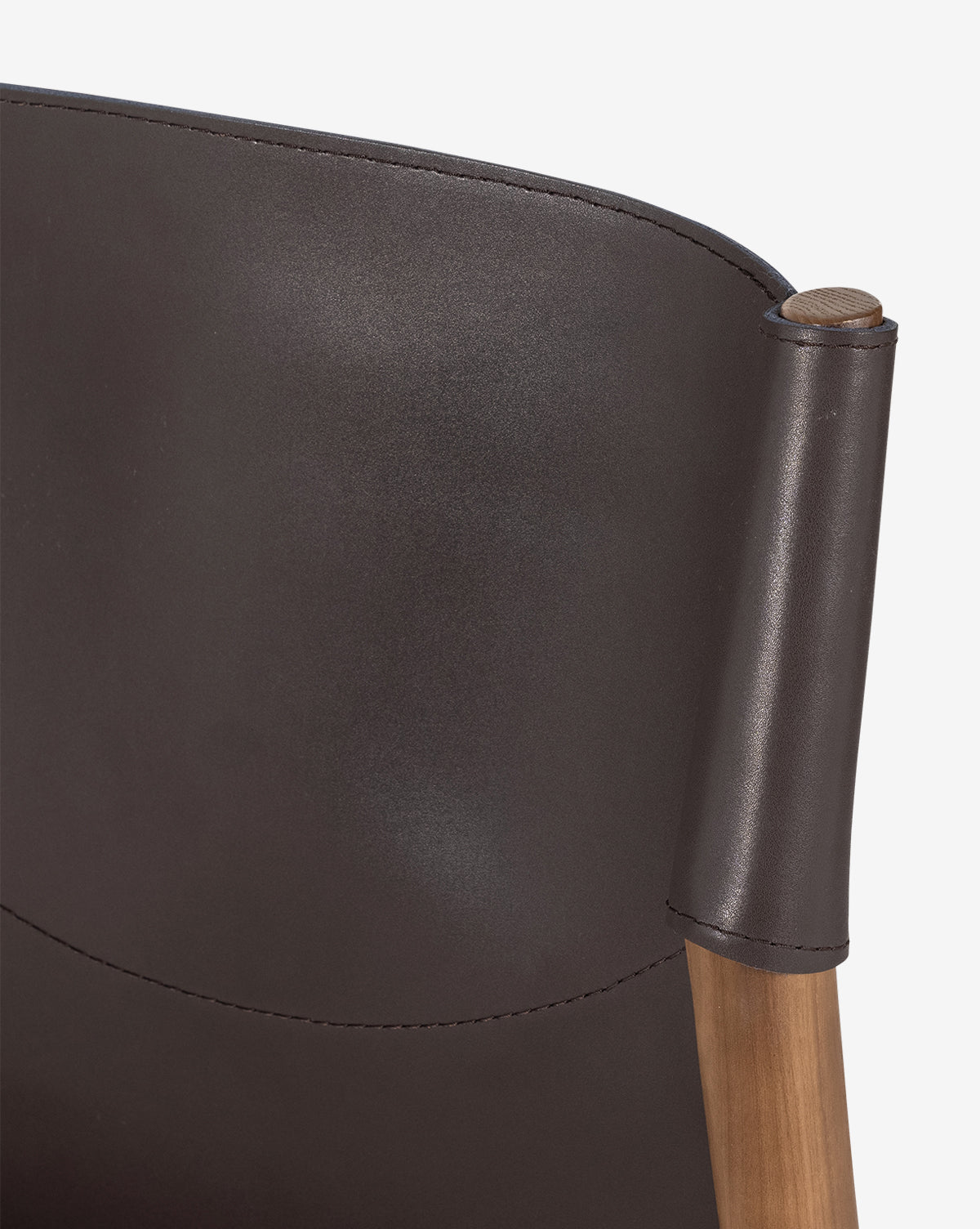 Close-up of the Kelby Dining Chair’s backrest, showcasing smooth espresso leather upholstery over a rounded ash wood frame, by McGee & Co.