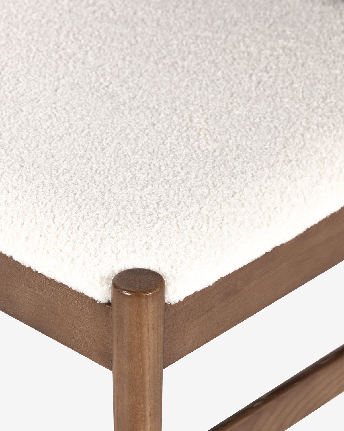 A close-up of the Kelby Dining Chair seat highlights its soft, white textured cushion and smooth ash wood frame with rounded edges, by McGee & Co.