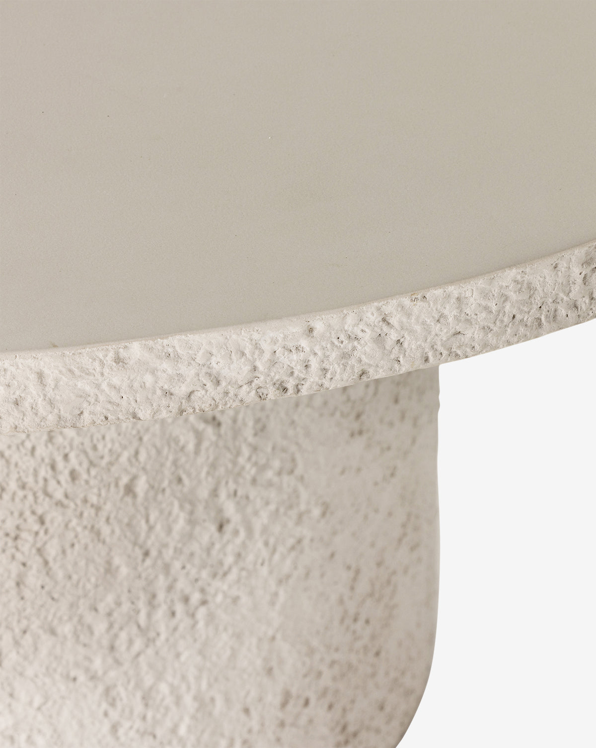 Close-up of the Atalanta Outdoor Dining Table, featuring a round, textured concrete design with a smooth top and rough, grainy edge and base in light beige—ideal for contemporary outdoor dining spaces, by McGee & Co.