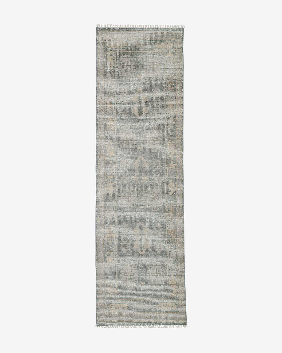 The Roslin Hand-Knotted Wool Rug is rectangular with a faded vintage-style pattern in muted blue and beige, featuring subtle geometric and floral motifs plus short fringe on the shorter ends, by McGee & Co.