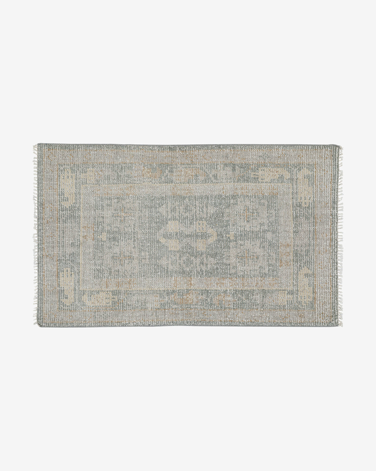 The Roslin Hand-Knotted Wool Rug is a rectangular, vintage-style wool rug with a faded floral pattern in muted blue and beige tones, finished with short fringe on the shorter edges, by McGee & Co.