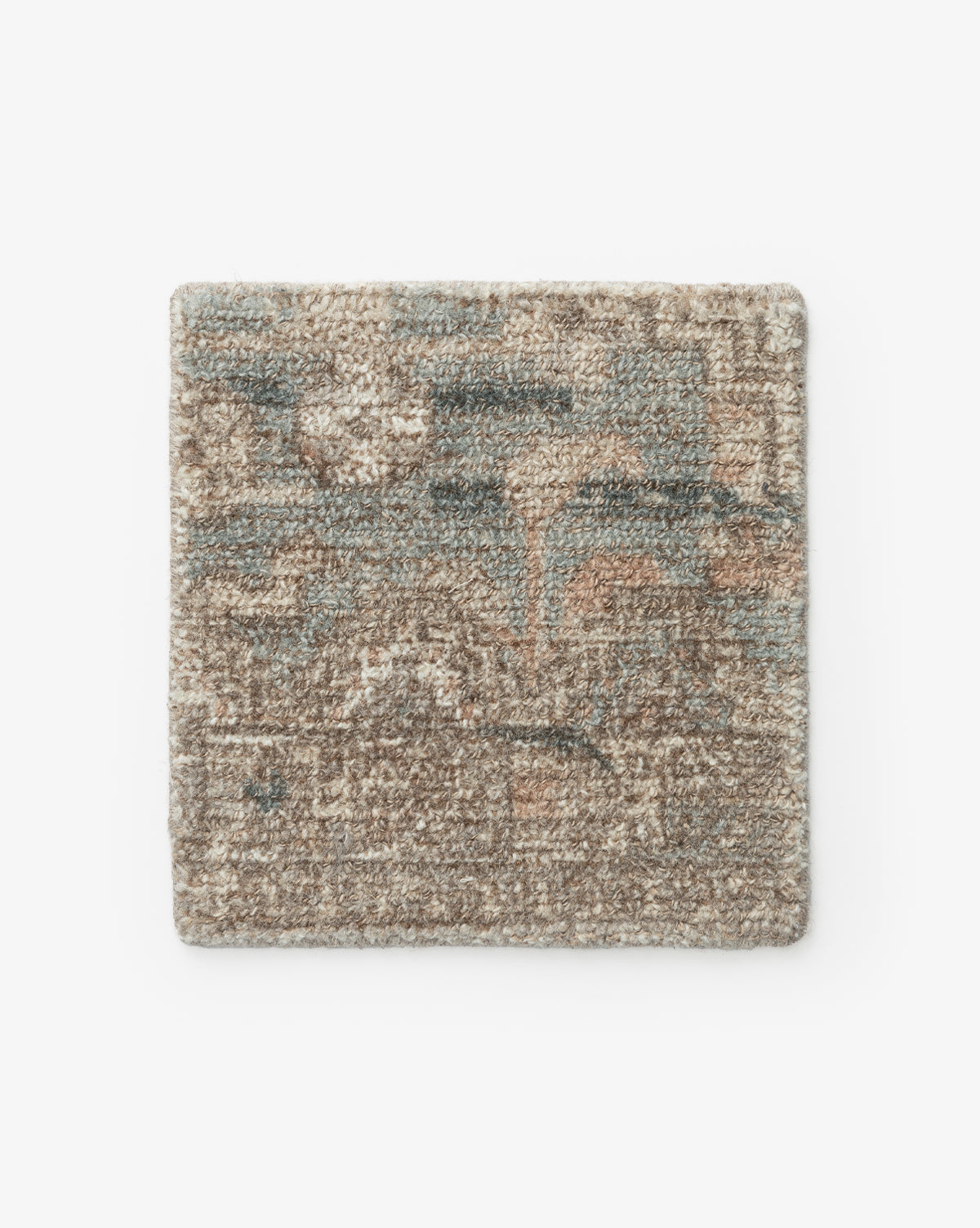 The Wilshire Blue Rug Swatch is a square, hand-tufted wool sample with a textured surface in muted brown, beige, blue, and peach hues. It features an abstract design and is shown on a plain white background by McGee & Co.