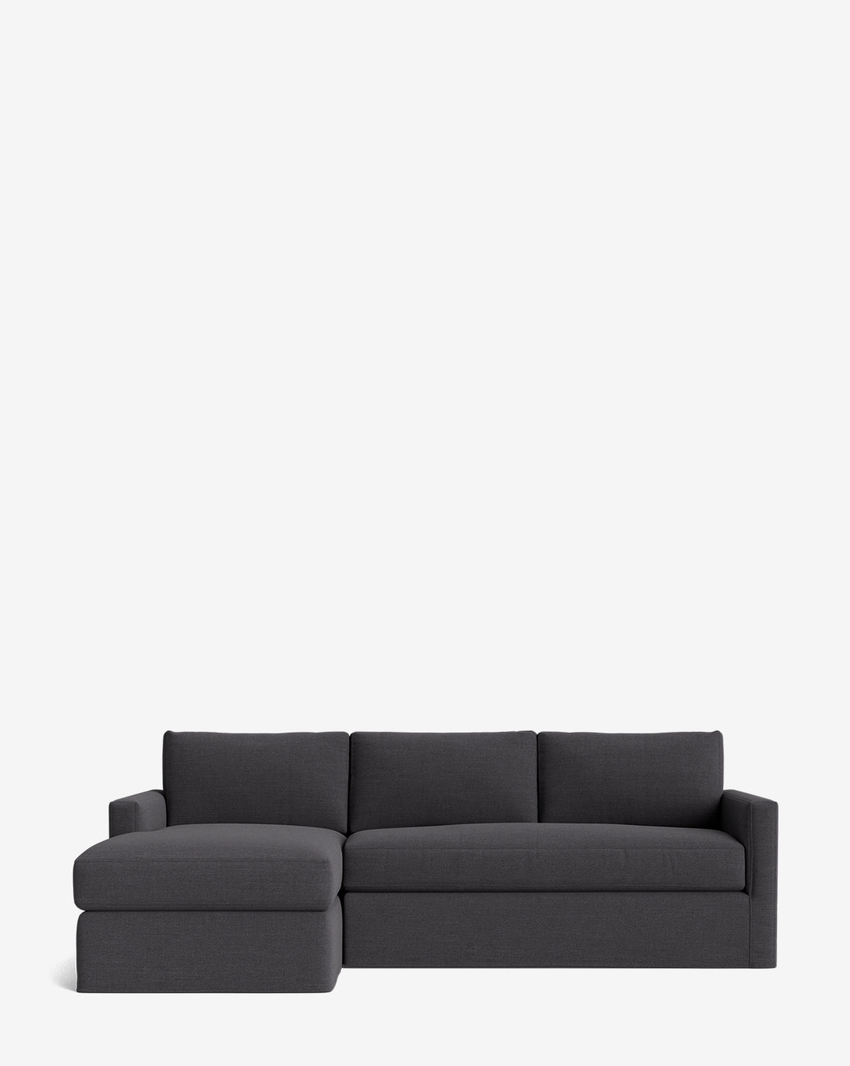 The Community Macy Slipcover Chaise Sectional 101 in modern dark gray features three seat cushions, a left chaise lounge, and a sleek, deep design—perfect for contemporary spaces. Shown against a plain white background. Customizable for your style. McGee & Co.