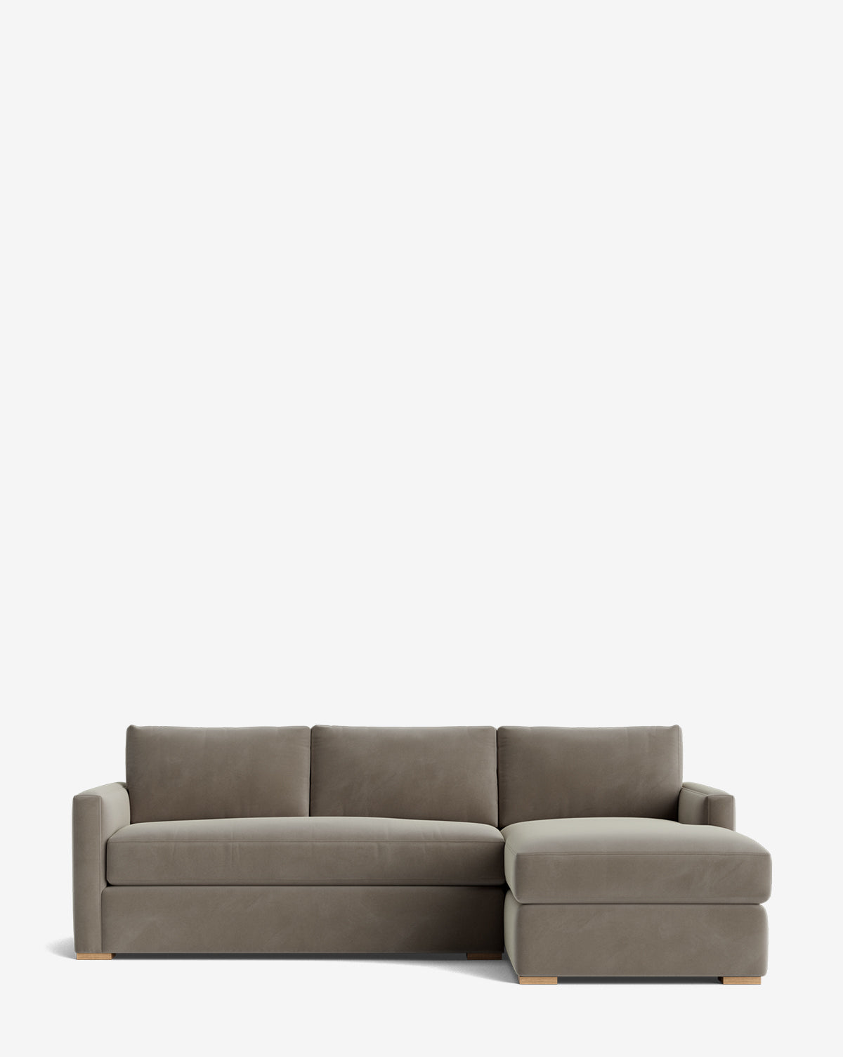 The Macy Upholstered Chaise Sectional 101 is a grey sofa with clean lines, three seat cushions, an upholstered right-facing chaise, low square arms, and light wooden block feet. Set against a plain white background by McGee & Co.