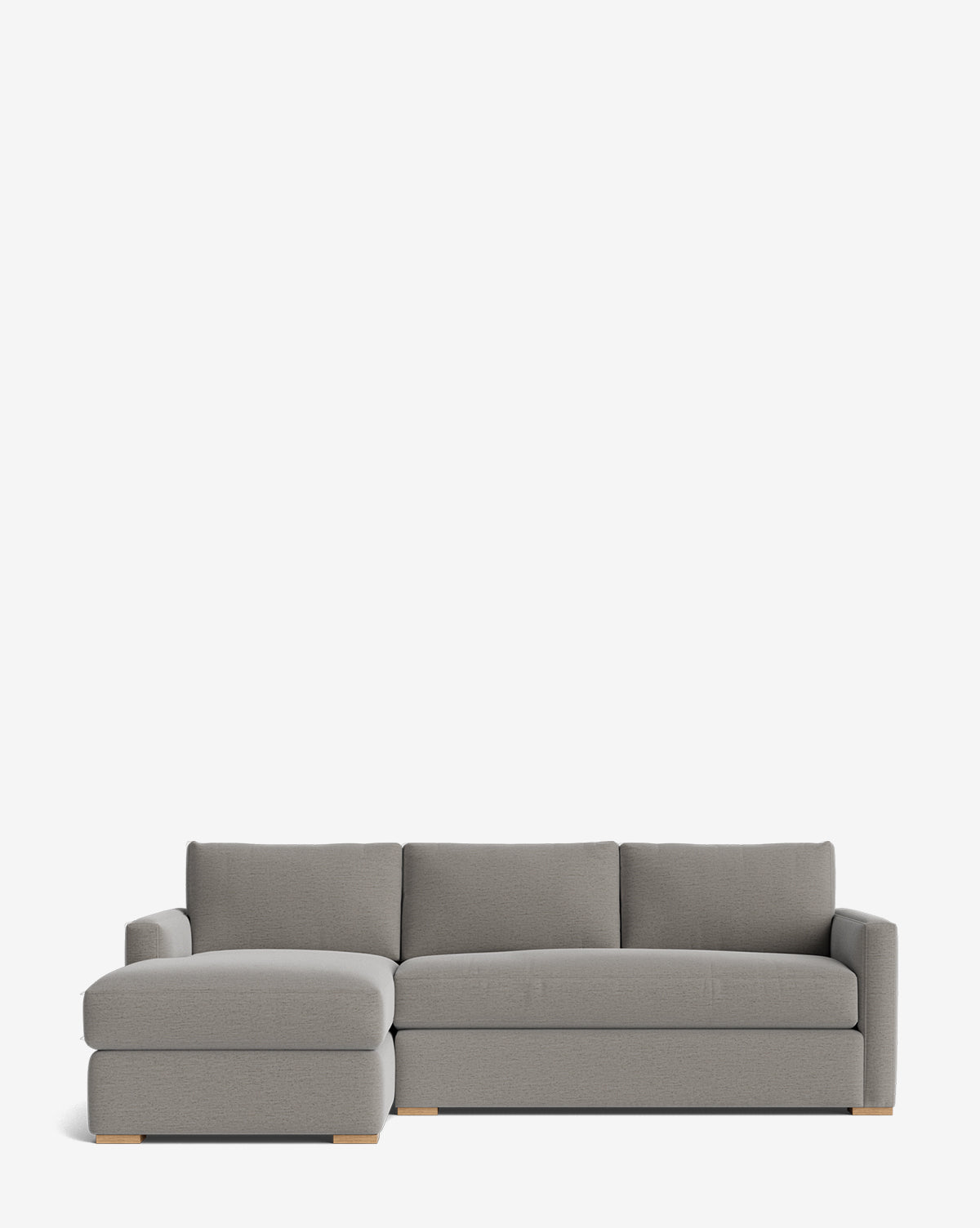 The Community Macy Upholstered Chaise Sectional 101, in modern gray with three back cushions, a left-side chaise lounge, and low wooden block feet, is shown against a plain white background, McGee & Co.
