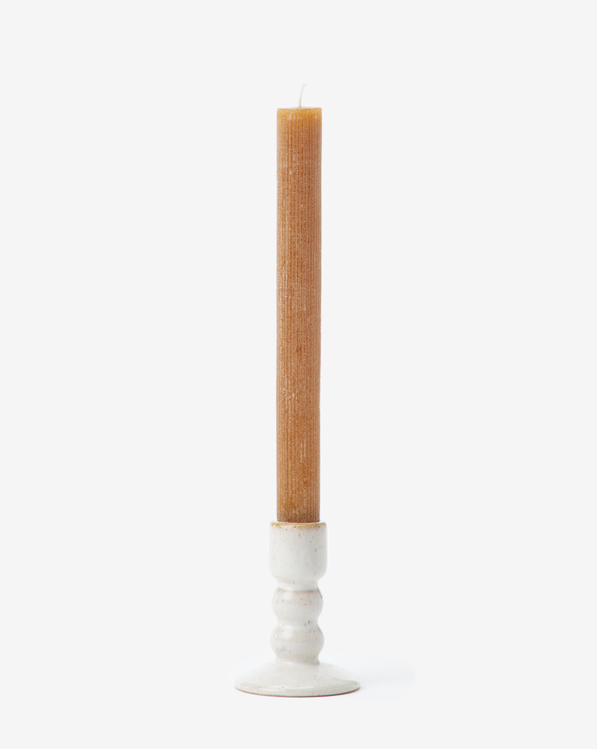 A tall, natural beeswax taper candle stands upright in the Mae Ceramic Taper Holder, a simple stoneware piece with a white glaze, set against a plain white background.