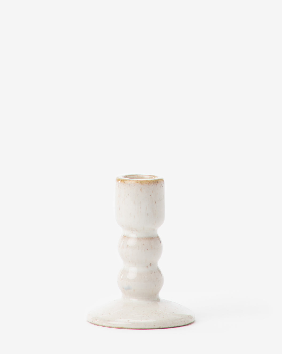 The Mae Ceramic Taper Holder is a small, white ceramic piece with a rounded, textured stem, wide base, and smooth glaze. Pictured against a plain white background.