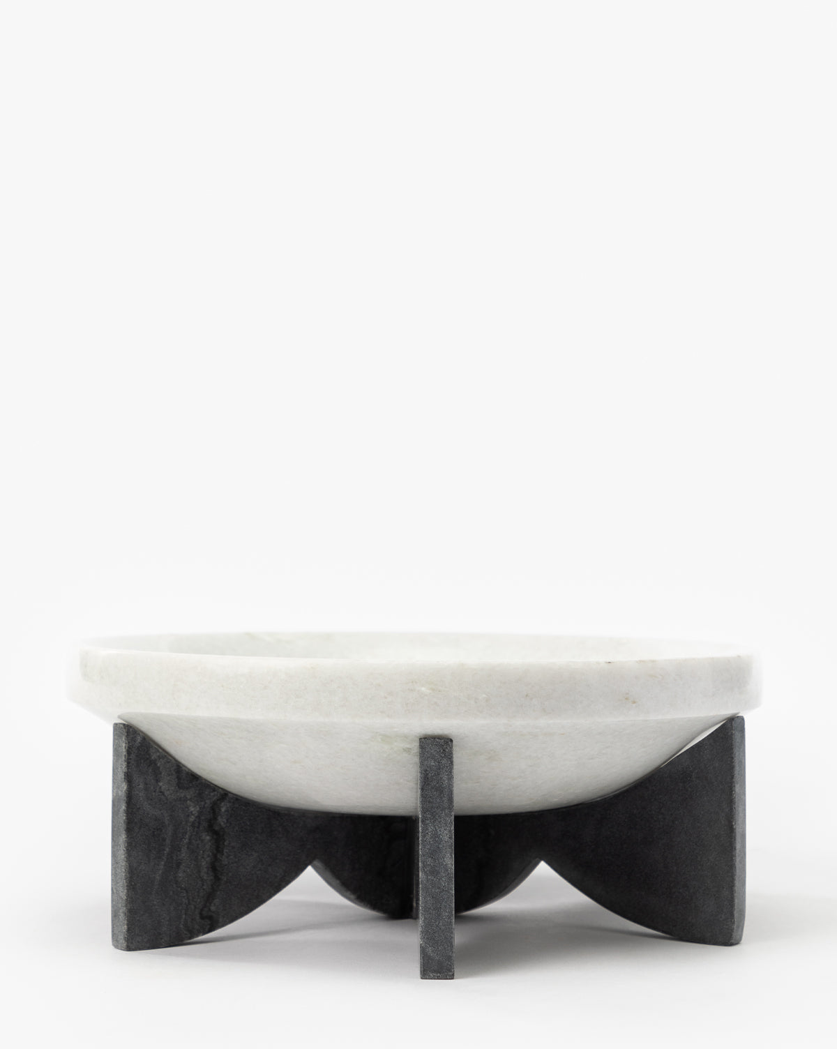 The Mahoney Bowl, crafted from white marble with a sculptural silhouette, sits atop a geometric black marble base featuring four intersecting supports, displayed against a plain white background by McGee & Co.