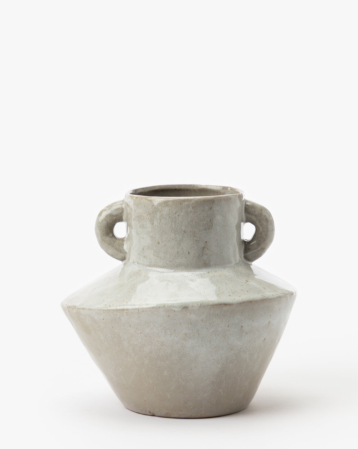 The Malaga Vase is a light gray stoneware piece featuring a wide, angular base, narrow neck, and two small rounded handles, finished with a white reactive glaze, shown against a plain white background.
