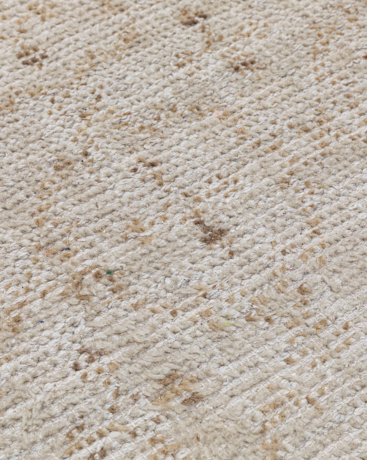 A close-up of the Mali Hand-Knotted Rug in beige, showing visible brown stains and an uneven texture, by McGee & Co.