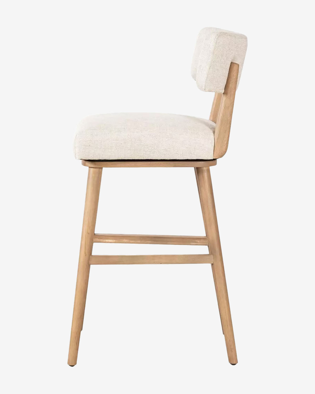 The Mance Swivel Stool by Four Hands features light wooden legs and an off-white cushioned upholstered seat and backrest, shown here from the side, available at McGee & Co.