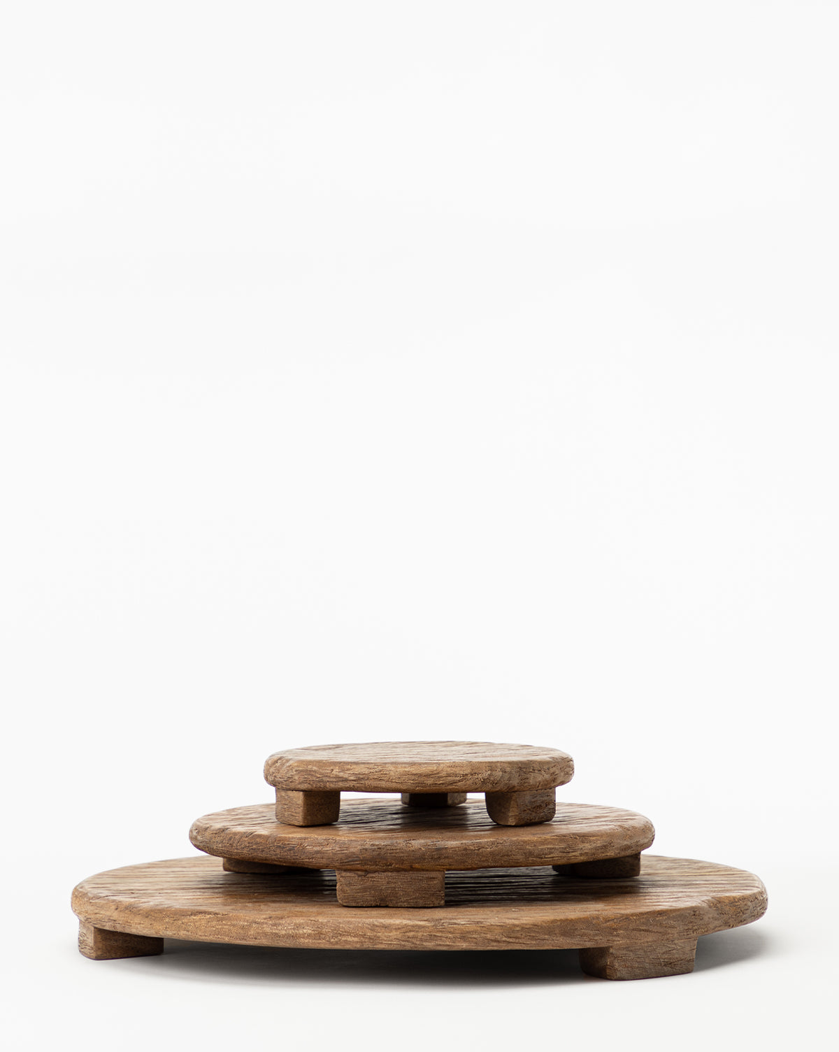 Three Mango Wood Carved Pedestals of varying sizes are stacked, each elevated by short legs, creating a stylish serving tray set displayed against a plain white background.