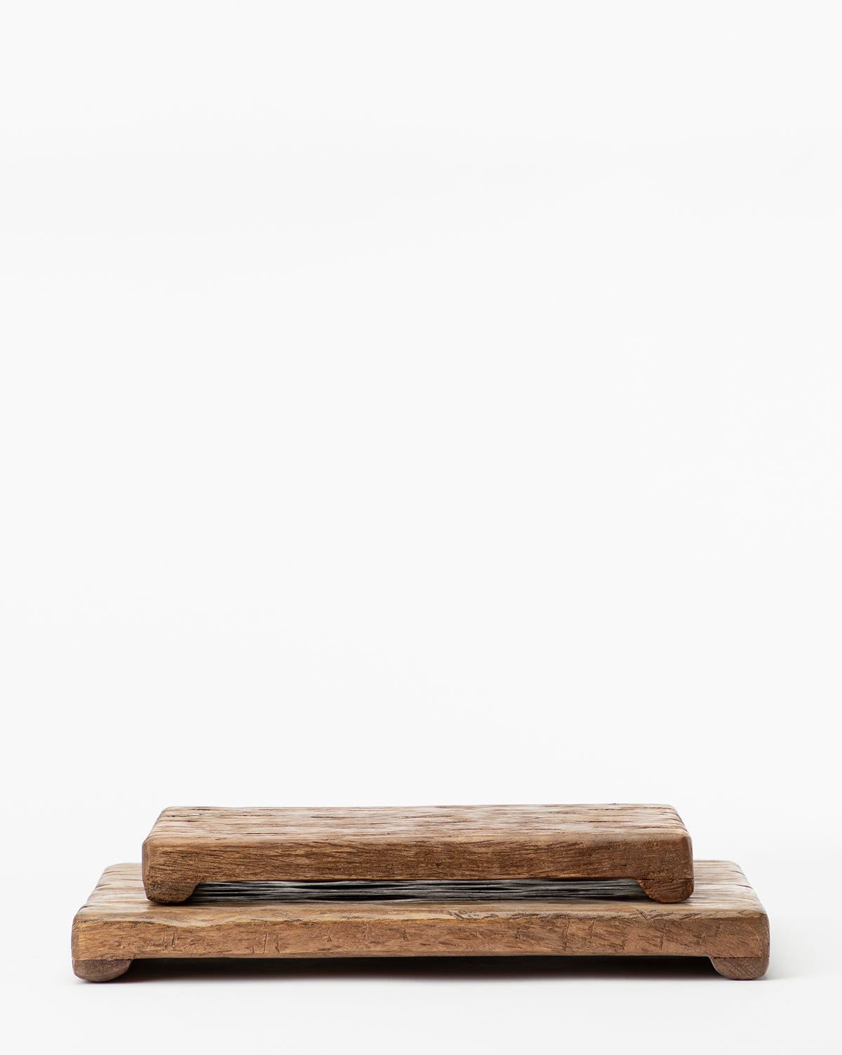 Two Mango Wood Rectangular Pedestals with a weathered finish and sturdy legs are stacked against a white background, offering a stylish and safe way to display food with natural rustic charm.