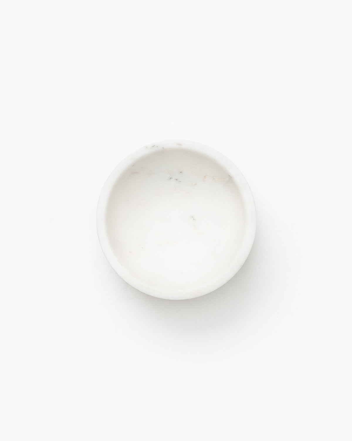 A small, round, white Marble Nesting Bowl (from the Set of 3) is shown empty from above against a plain white background. Its smooth, minimalist look adds a subtle designer touch and is perfect for nesting with the other bowls in the set.