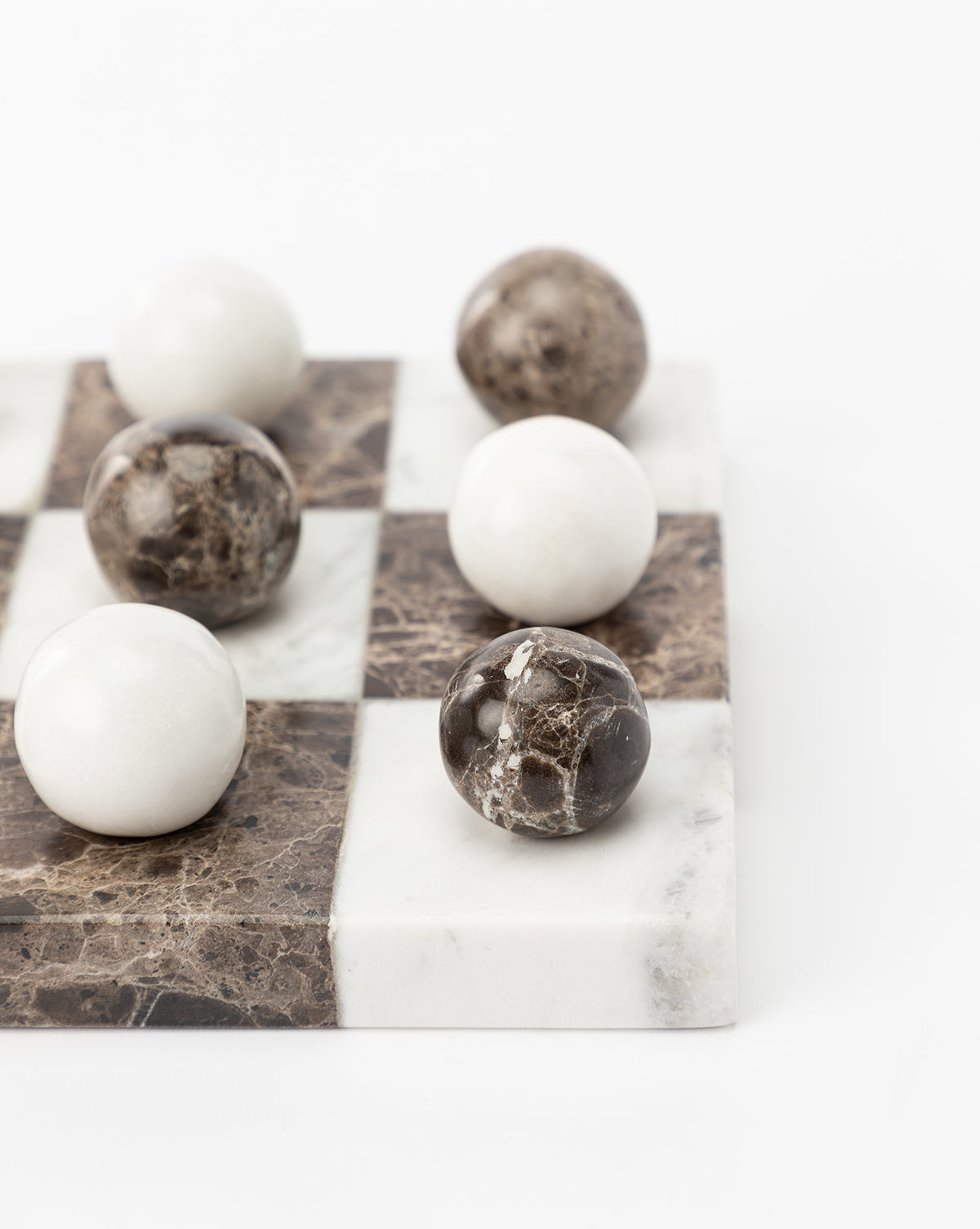 A close-up of the Marble Tic-Tac-Toe Board, featuring large white and brown marble spheres on alternating squares—perfect as elegant marble coffee table decor, displayed against a white background.