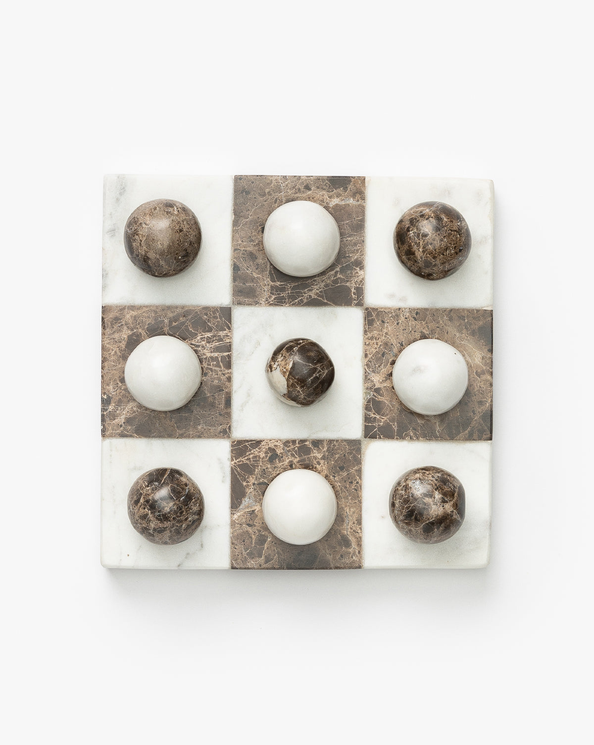 The Marble Tic-Tac-Toe Board features alternating white and brown marble squares with matching round playing pieces—an elegant game board ideal for stylish coffee table decor.
