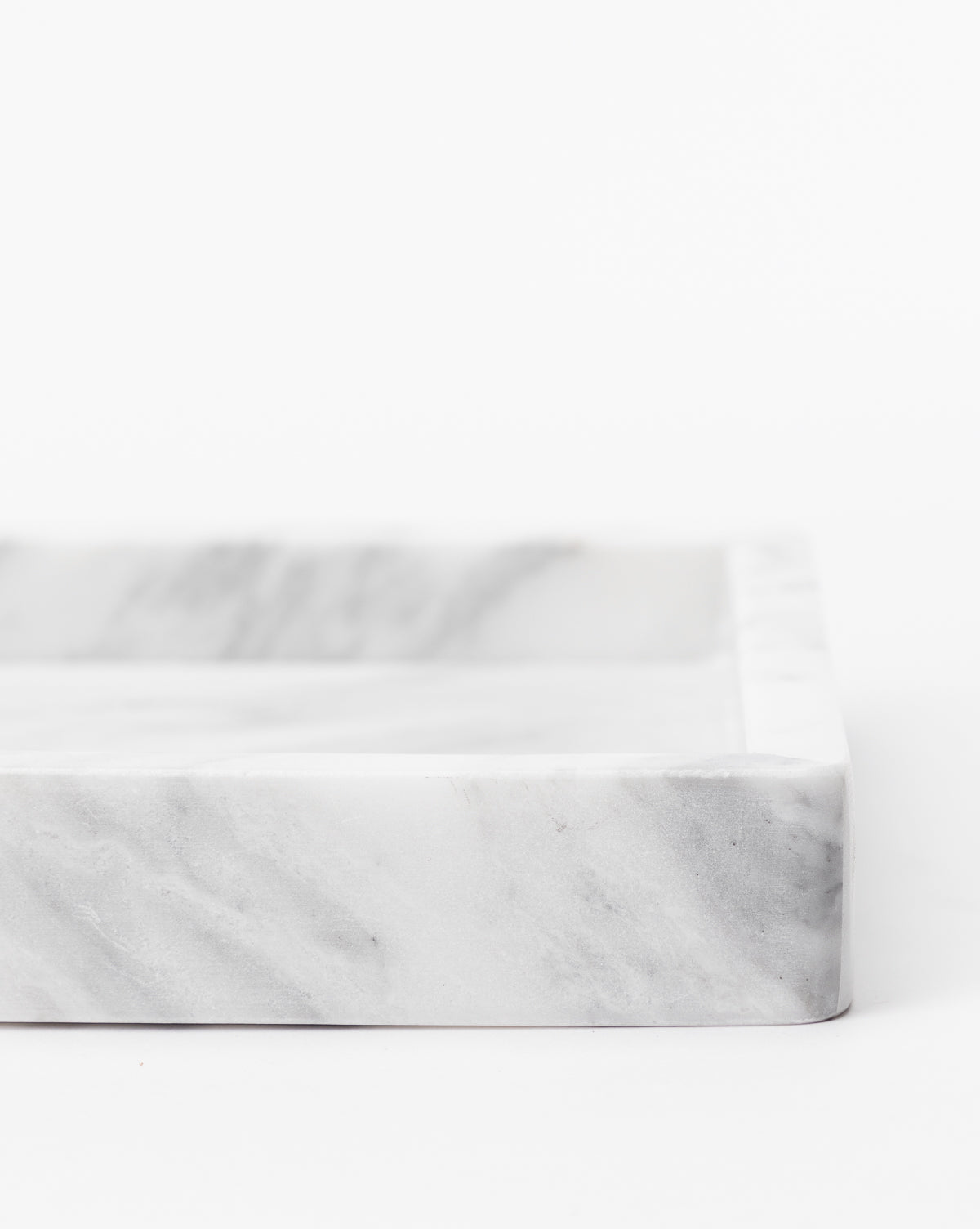 A close-up of the Marble Tray, featuring subtle gray veining and a rectangular shape, ideal as a countertop tray for decorative vignettes, set against a plain white background.