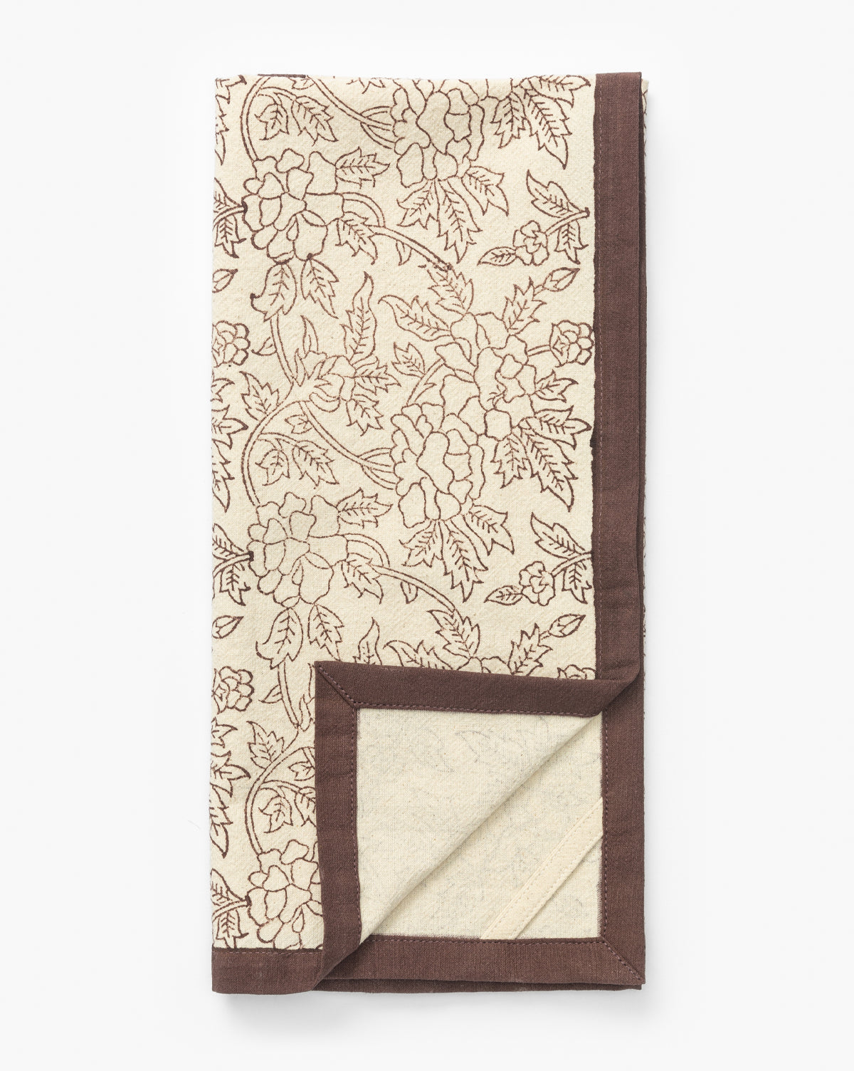 The Marceline Cotton Tea Towel, in cream with a brown floral pattern and border, is block printed for charm and shown folded with a corner turned up—an elegant accent for your kitchen decor, by McGee & Co.