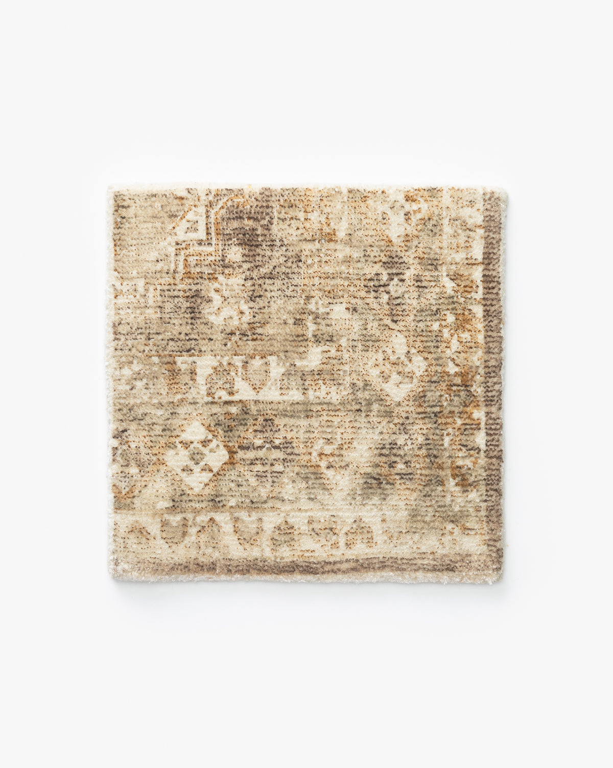 The Marcella Rug Swatch is a rectangular, handwoven piece featuring a faded, vintage-inspired pattern in beige, cream, and light brown tones on a plain white background by McGee & Co.