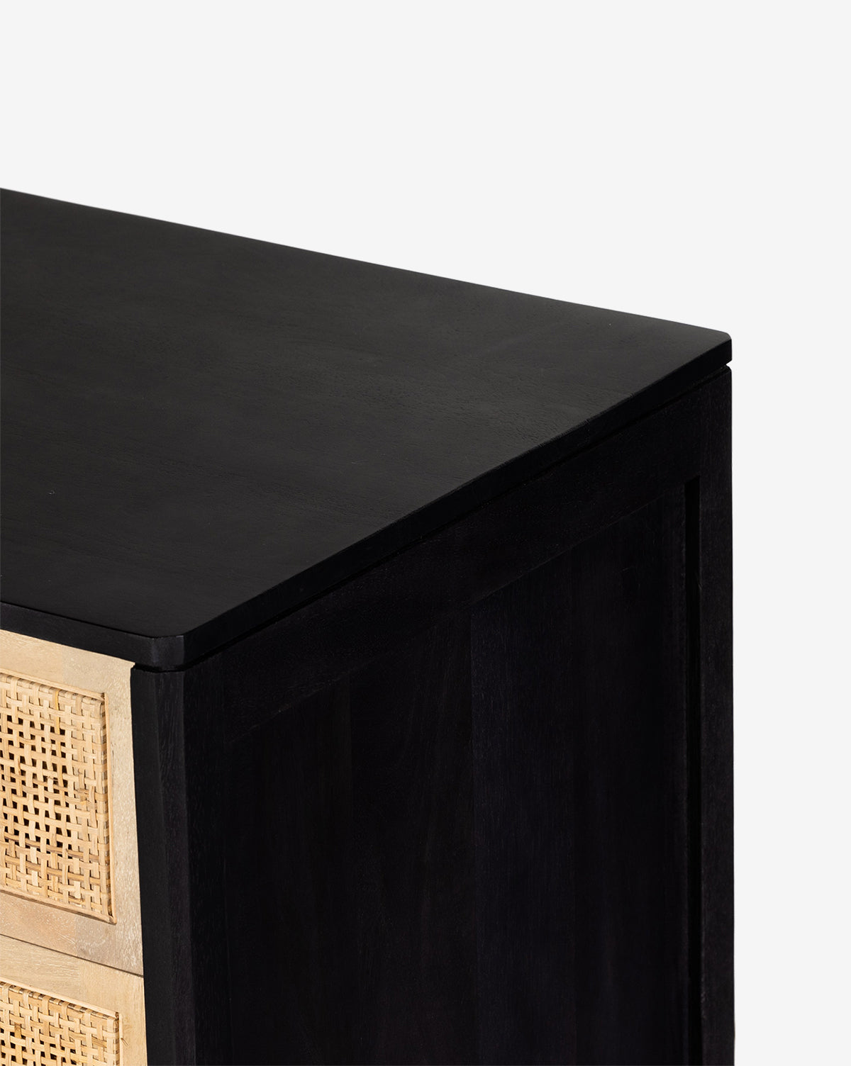 A close-up of the top corner of the Margaery Nightstand, featuring black solid wood and a natural woven cane front drawer, set against a plain white background, by McGee & Co.