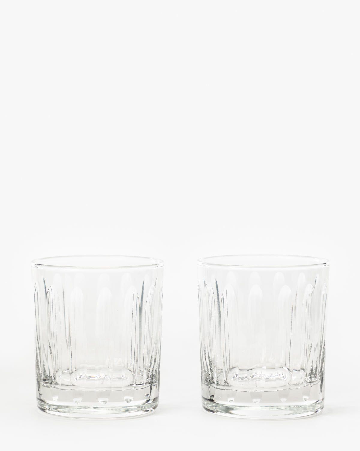 Two empty, clear Marick Tumblers (Set of 2) featuring subtle vertical patterns and classic silhouettes are placed side by side on a plain white background, by McGee & Co.
