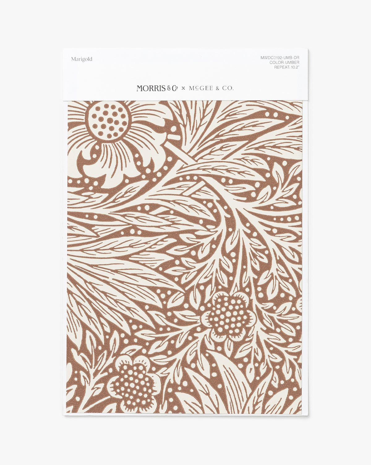 The Morris & Co. x McGee & Co. Marigold Umber Wallpaper Swatch features a brown and white marigold floral pattern with intricate leaves, packaged with a white label branded “McGee & Co.” McGee & Co.