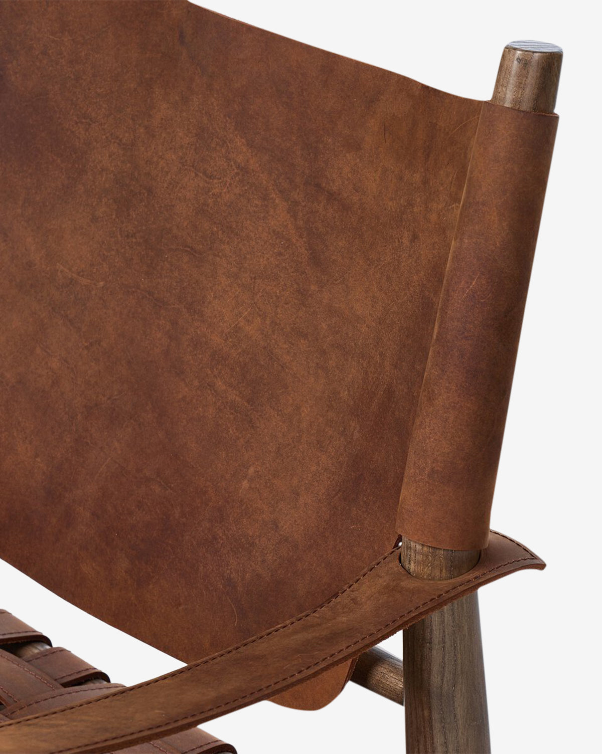 Close-up view of the Maris Lounge Chair, featuring a brown top-grain leather backrest and seat, wooden frame with rounded armrests, and vintage-style texture and stitching details, by McGee & Co.