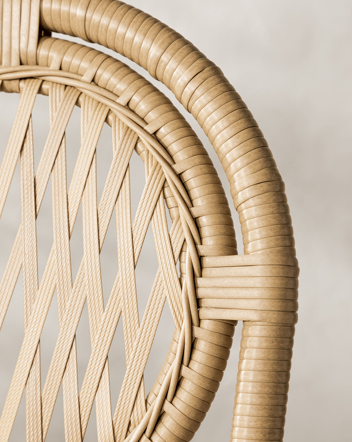 Close-up of the Marisol Indoor/Outdoor Counter Stool by Makerspalm, showing its handwoven wicker backrest with interlaced diagonal strips and a smooth circular frame in light tan, set against a neutral, blurred background. Set of 2. McGee & Co.