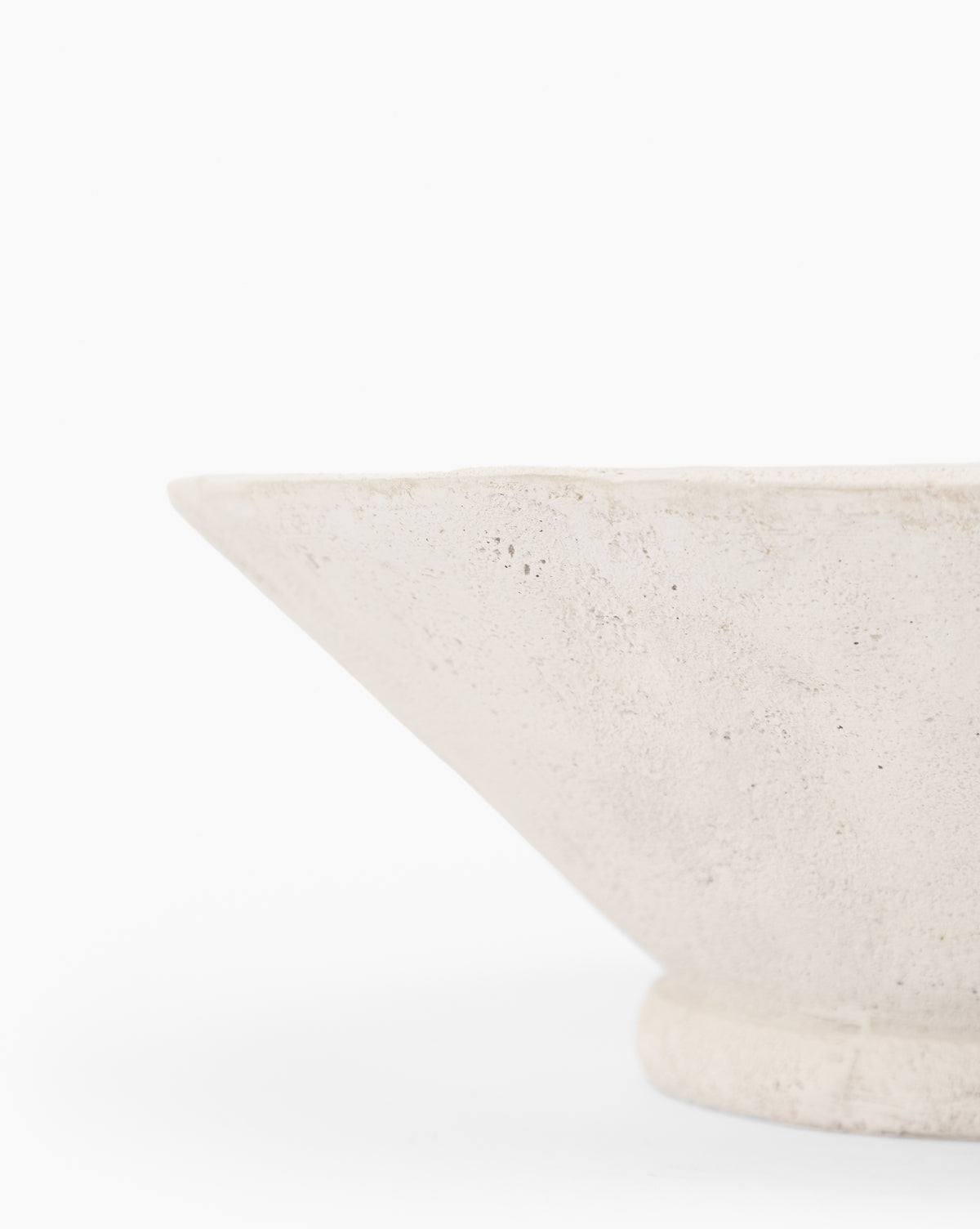 A close-up shows part of the Matias Bowl’s textured, weathered white edge, set against a plain white background, highlighting its angled, geometric shape.