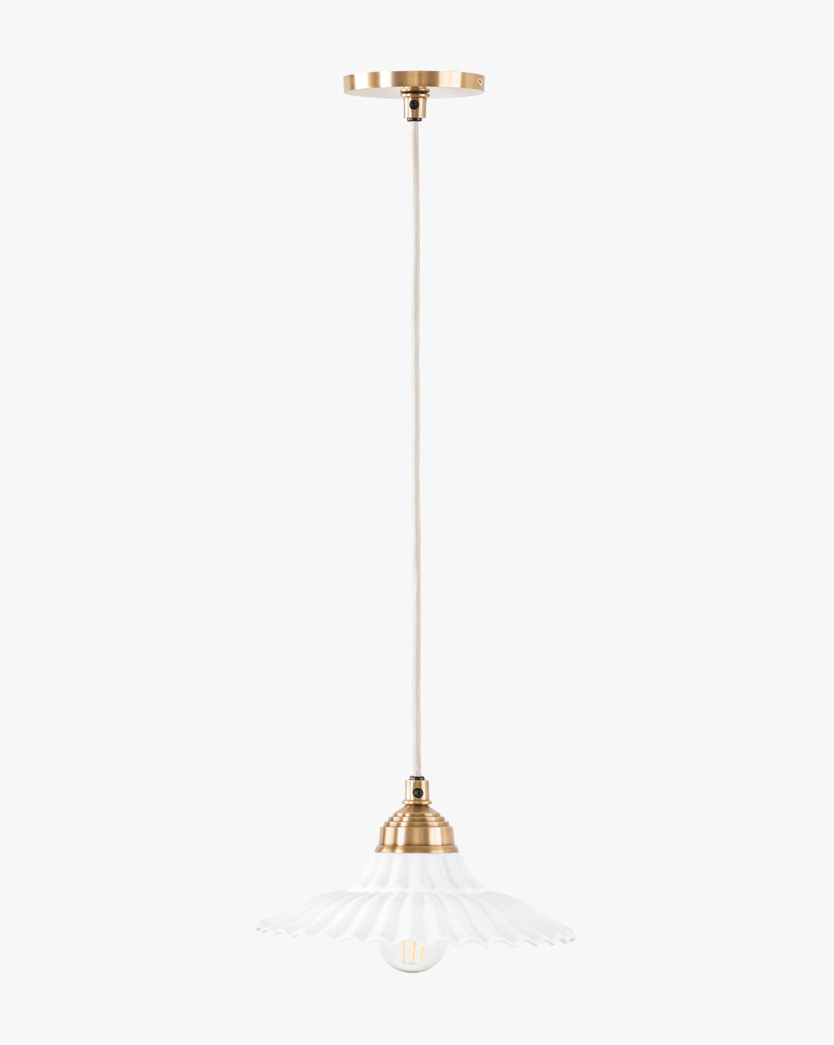 The McGee & Co. x Loeffler Randall Maude Glass Pendant features elegant brass hardware, a beige cord, and a white fluted glass shade suspended gracefully from the ceiling by McGee & Co.