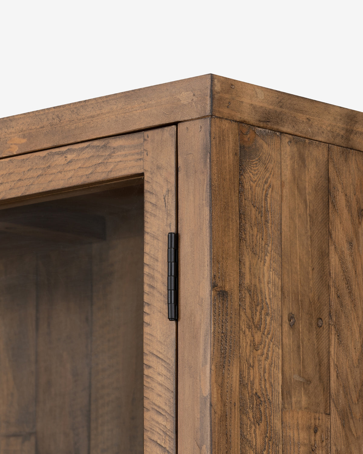 Close-up of the Maverick Cabinets top corner shows its reclaimed pine construction, glass-paneled door, and visible iron hardware, highlighting the wood grain and texture against a plain white background, by McGee & Co.