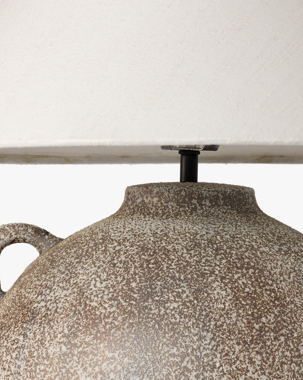 Close-up of the Mays Table Lamps textured, speckled ceramic base—evoking vintage clay jars—paired with a light beige fabric shade. The image focuses on the upper base and lower edge of the lampshade, by McGee & Co.