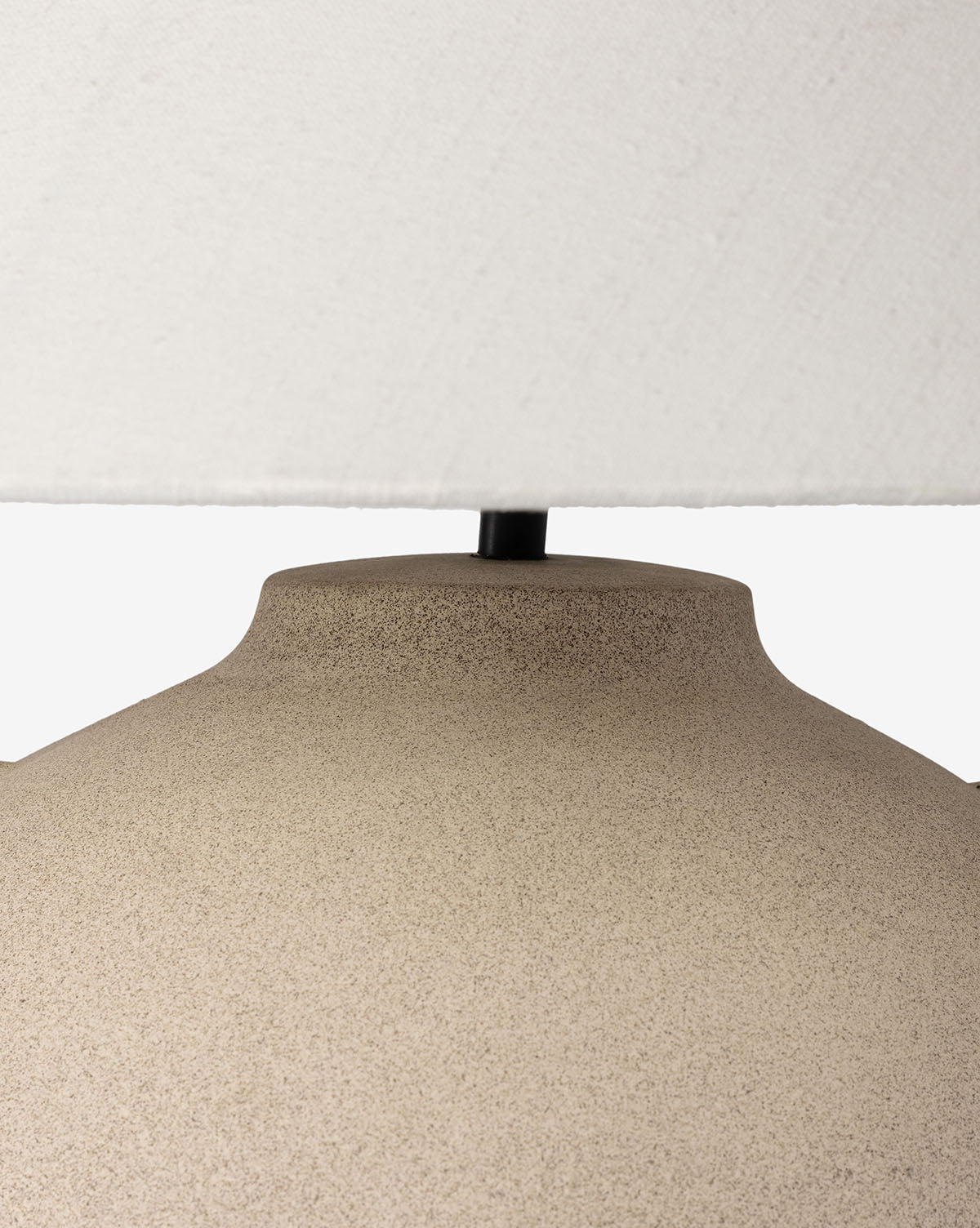 Close-up of the top portion of the sand-colored Mays Table Lamp base with a white fabric lampshade above it, set against a plain background by McGee & Co.