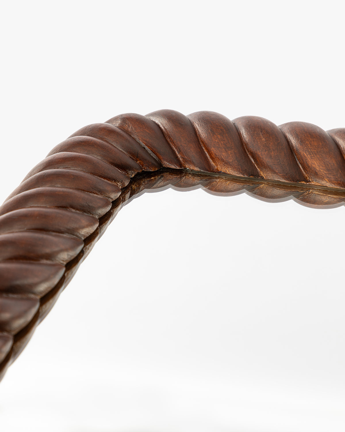 Detailed view of the Mayweather Wall Mirror’s dark red walnut frame, featuring a twisted rope design with a smooth, polished finish, forming an elegant corner against a white background, by McGee & Co.