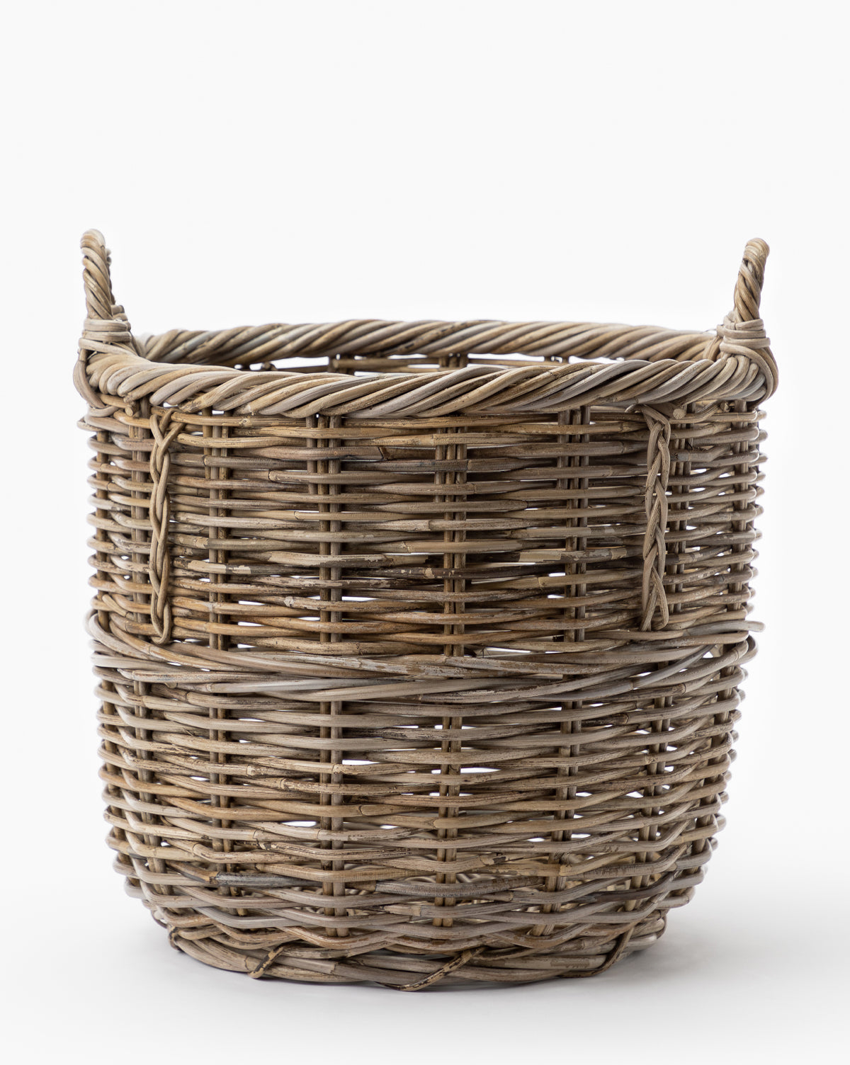The Mckell Basket is a round, woven wicker basket made from natural materials, featuring two side handles and shown against a plain white background.