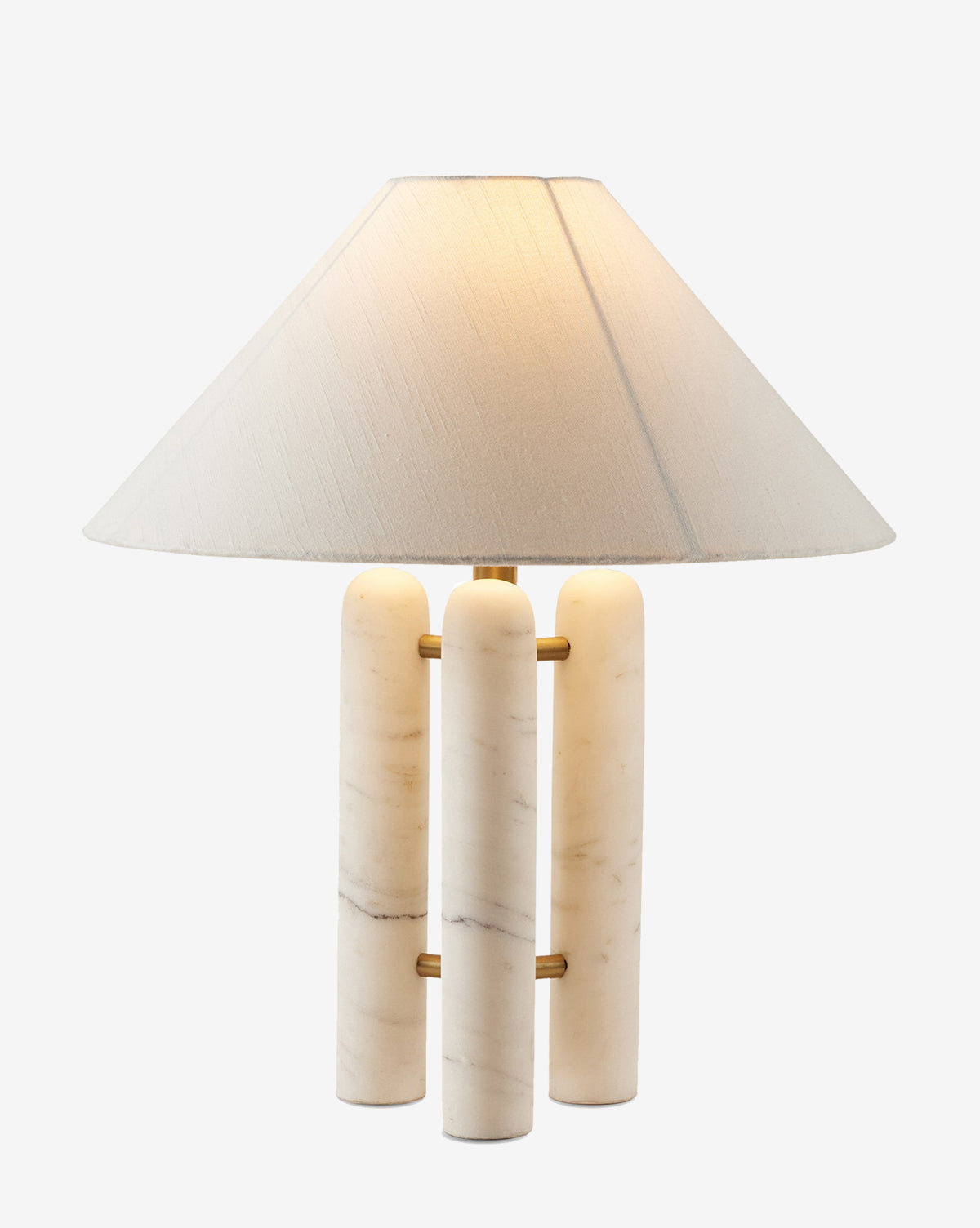 The Medici Table Lamp has a decorative design with a beige conical fabric shade and a solid marble base of three cylindrical columns joined by brass rods, casting a warm light when turned on, by McGee & Co.