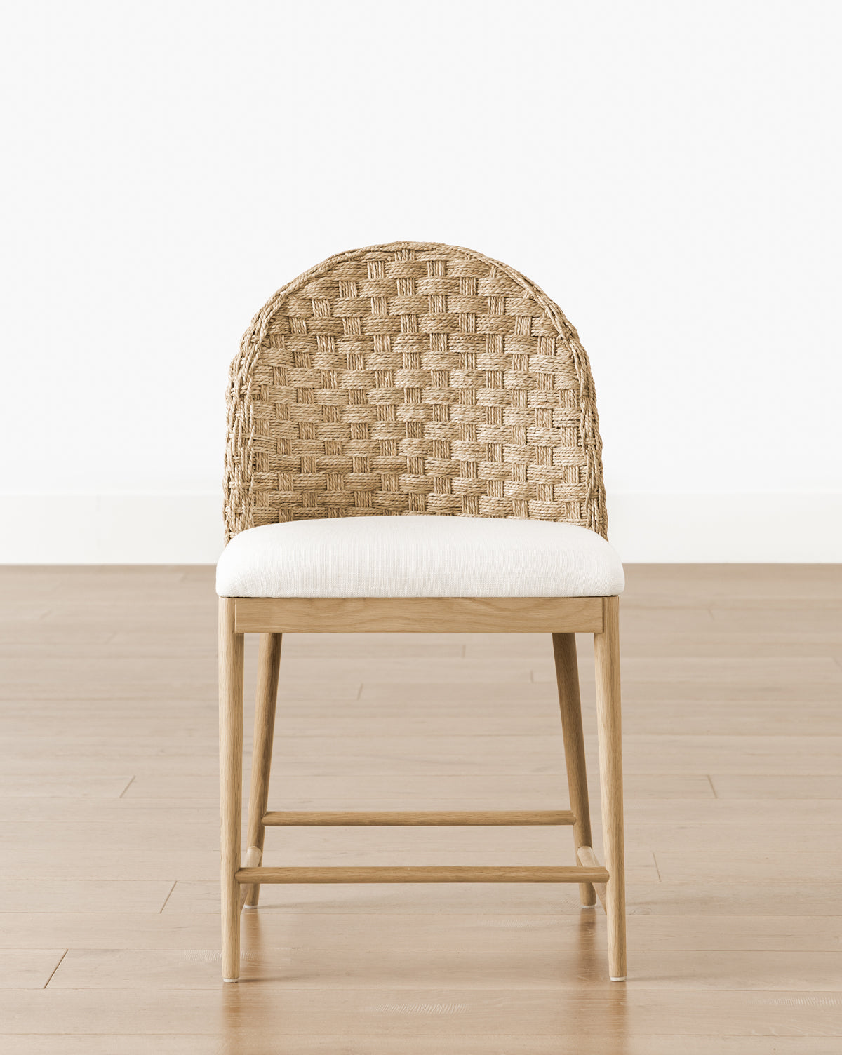 The Molly Dining Chair has a solid oak frame, woven rattan curved backrest, and white cushioned seat—an elegant modern chair that complements any space, by McGee & Co.
